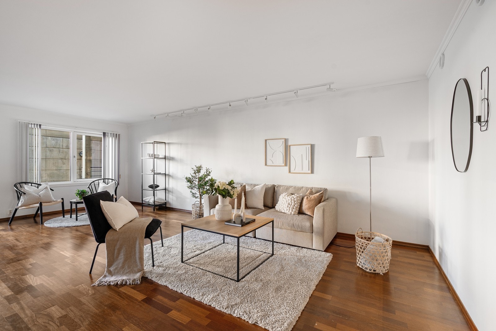 Romslig stue med lyse vegger og parkett på gulv Galleribilde