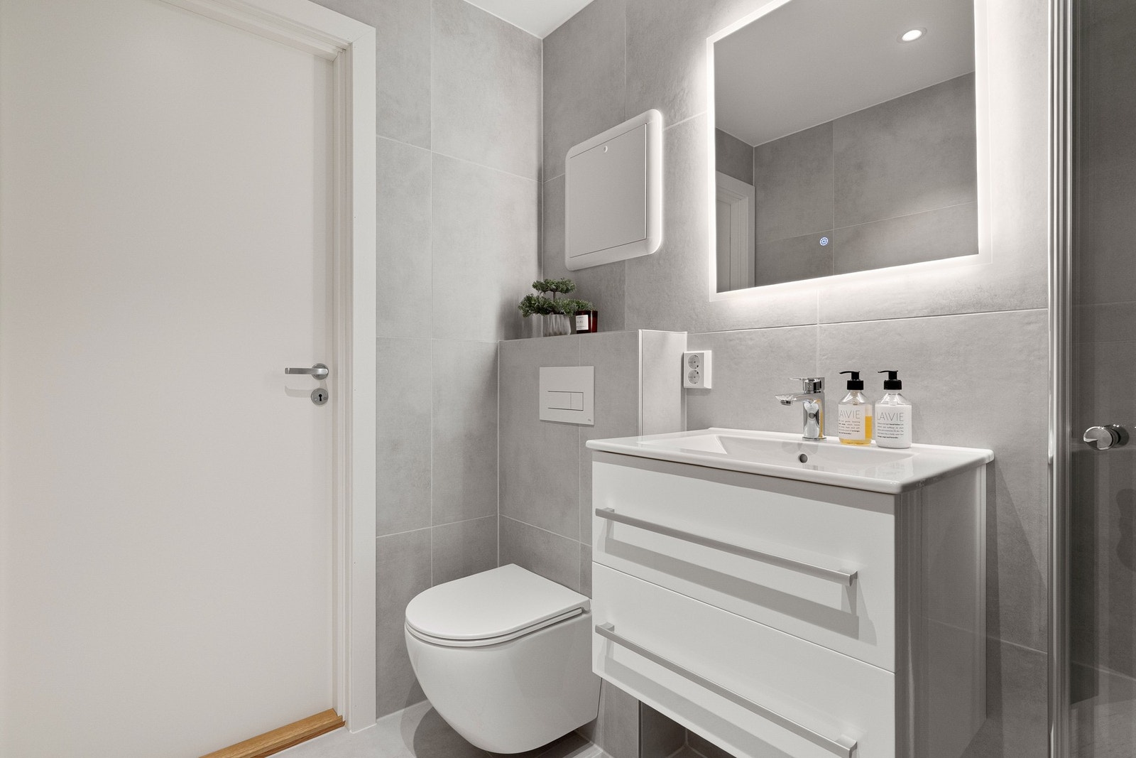 Lekre fliser og stilrene materialvalg. Moderne komfort med varmekabler og opplegg for vaskemaskin. Galleribilde