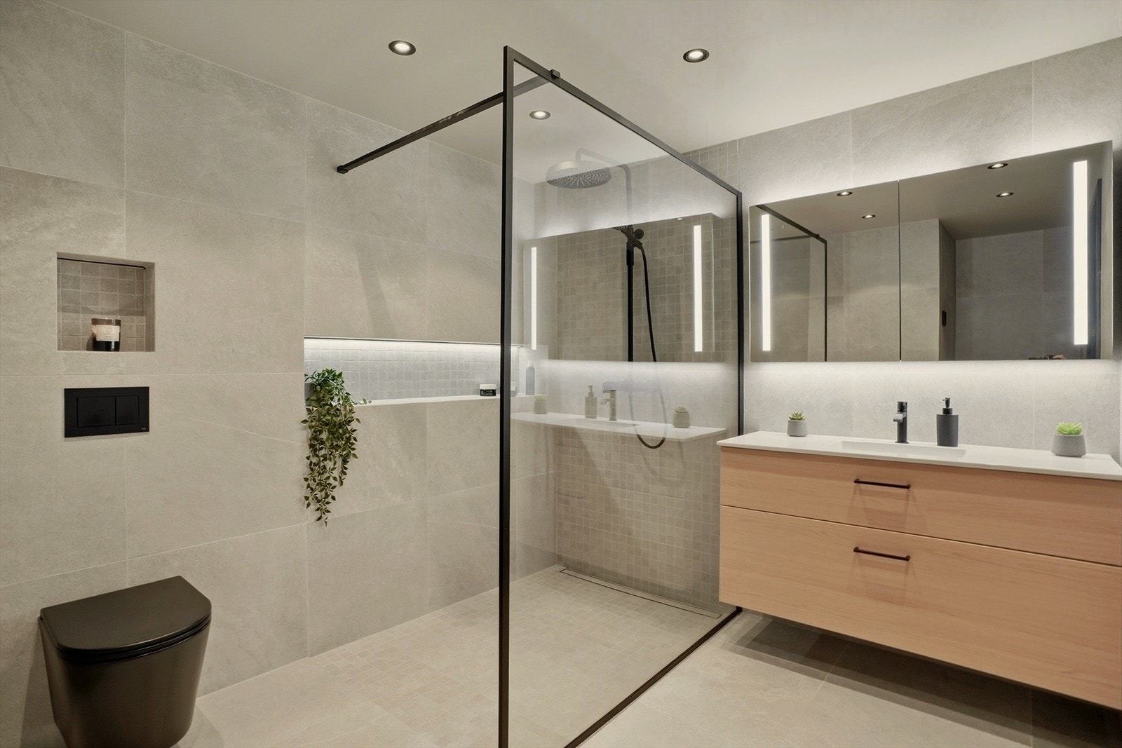 Dusjsonen er elegant avgrenset med glassvegg, og kombinasjonen av store fliser og mosaikk i dusjen gir en fin visuell kontrast. Galleribilde