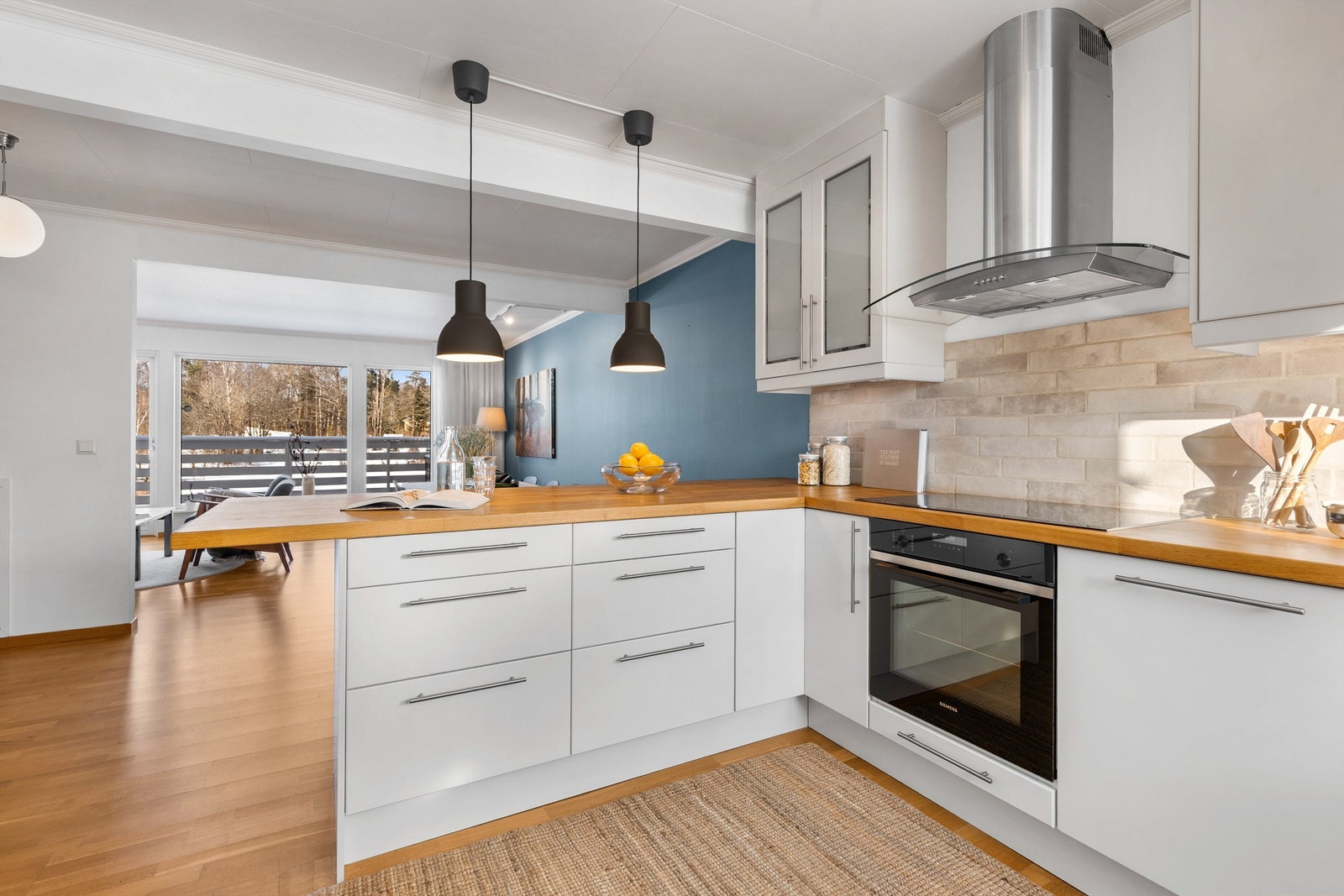 Åpen kjøkkenløsning. Kjøkkeninnredning med slette fronter. Benkeplate av tre. Nedfelt oppvaskkum i rustfritt stål med ett-greps armatur. Galleribilde