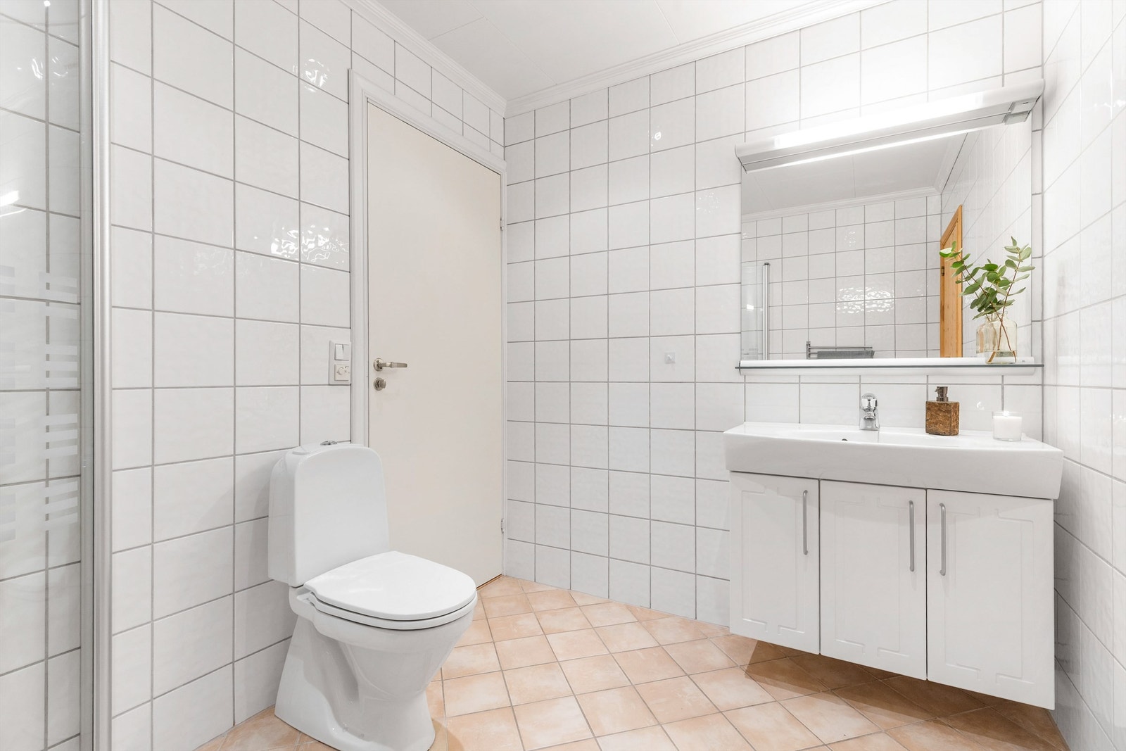 Baderom med flislagt gulv med varme og flislagte vegger. Nedsenket himling med downlights. Vegghengt servantskap. Ovenpåliggende servant med ett-greps armatur. Galleribilde