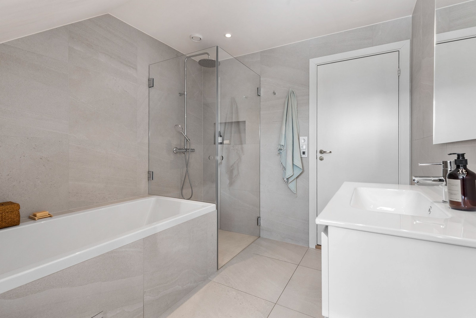 Speil med belysning samt stikkontakt på vegg over servant. Dusjsone med innfellbare dører av glass. Dusjarmatur tilkoblet hånddusj og regndusj. Nisje på vegg i dusjsone. Galleribilde