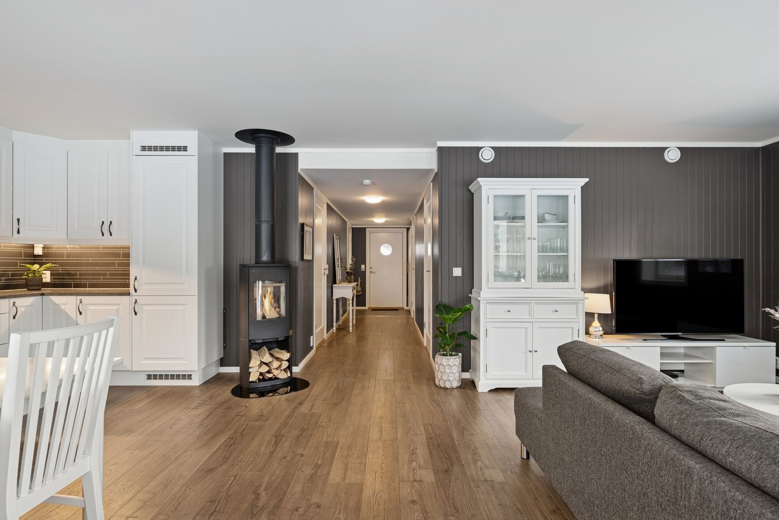 Åpen og praktisk romløsning der vedovnen står sentralt for effektiv varme, kombinert med balansert ventilasjon som gir optimal varmefordeling og komfort. Galleribilde