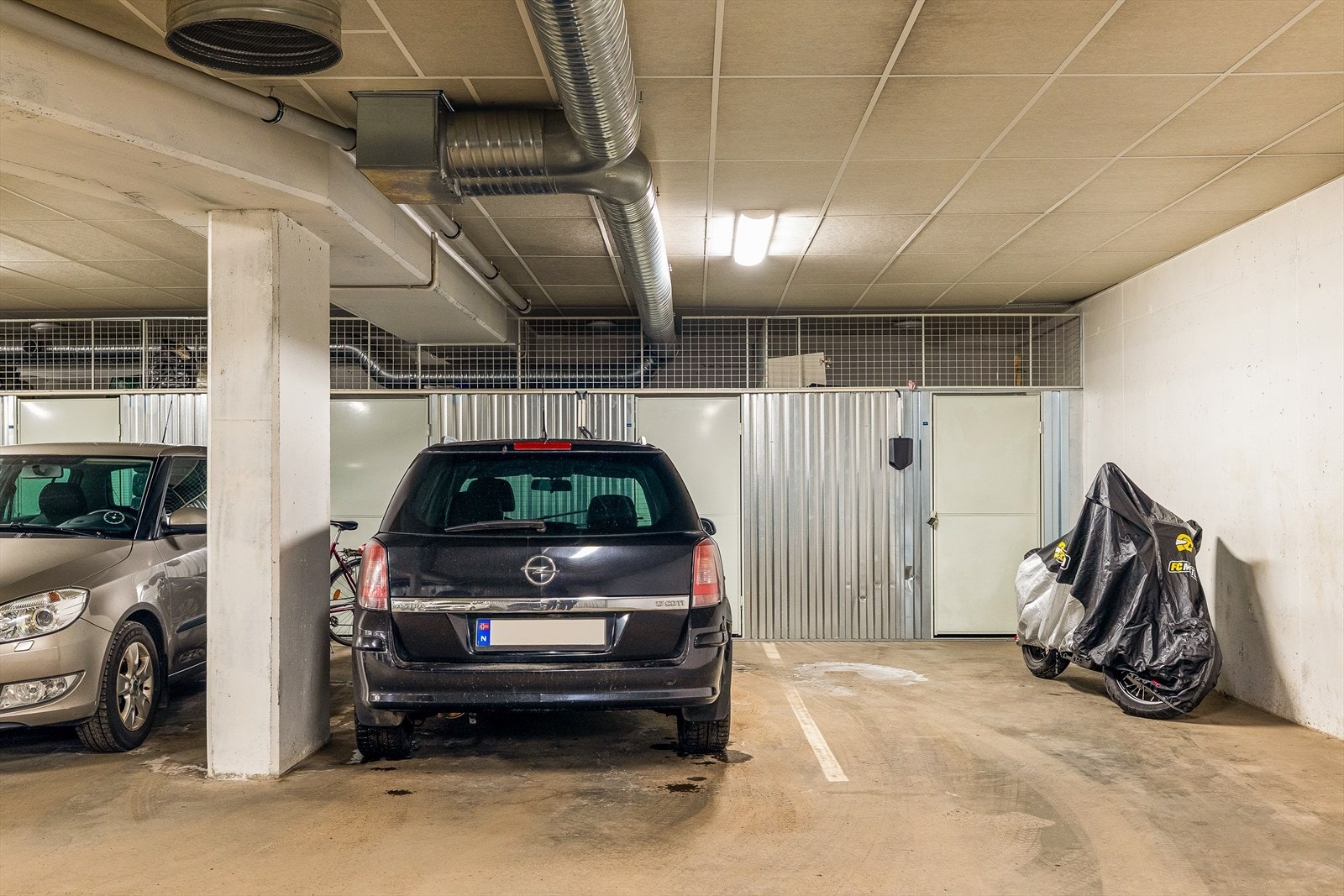 Leiligheten disponerer en garasjeplass i garasjekjeller, plassen har montert elbillader. Bildet er av en annen parkeringsplass. Parkeringsplassen er tilsvarende. Galleribilde