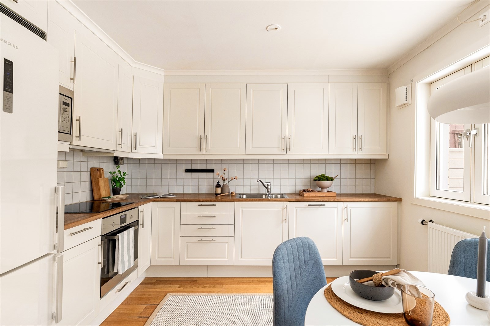 Klassisk kjøkkeninnredning med overflater som består av hvite profilerte fronter og benkeplate av laminat. Galleribilde