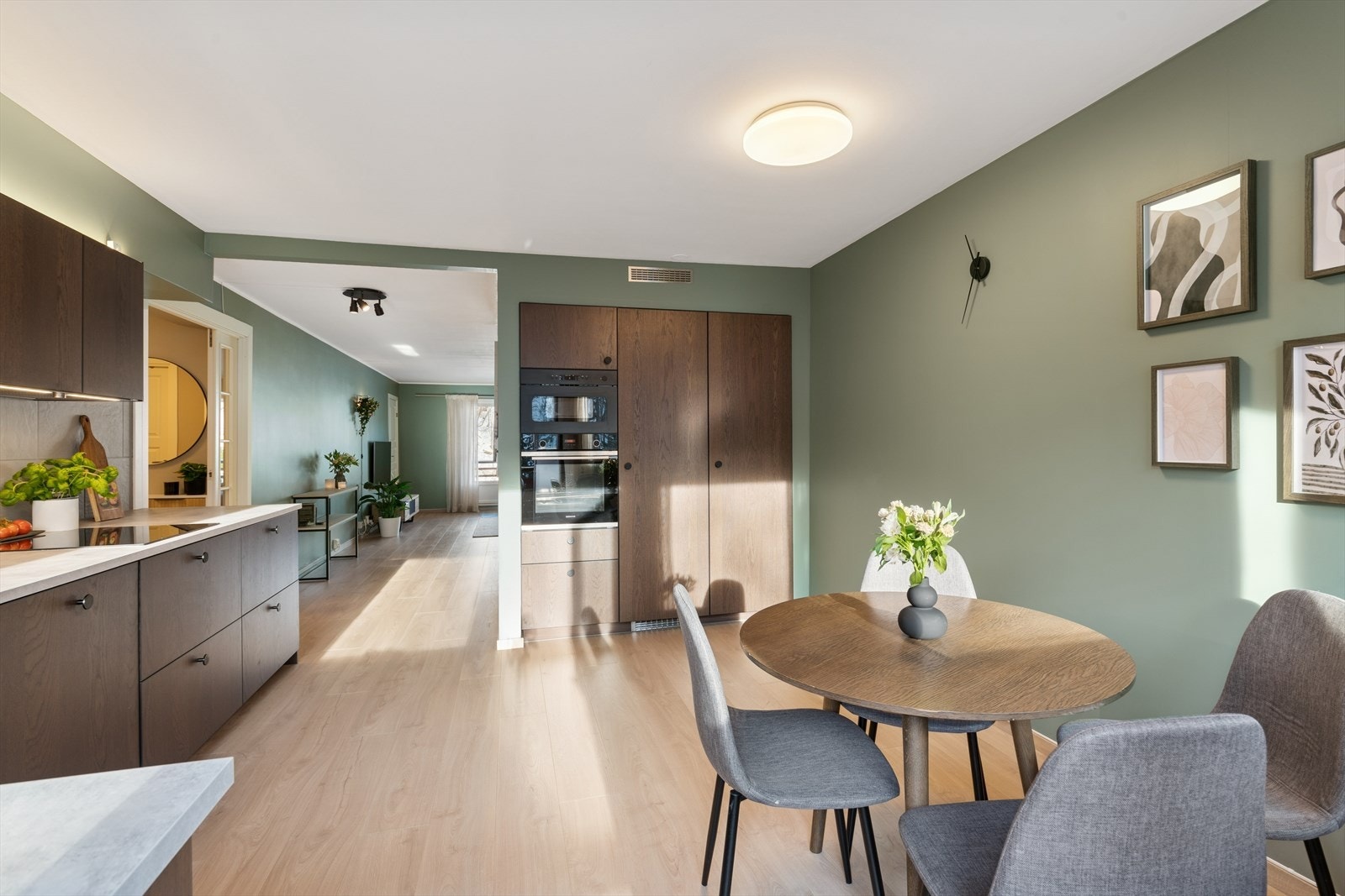 Kjøkkenet har glatte fronter, belysning under overskap og praktisk avlastningssone. Galleribilde