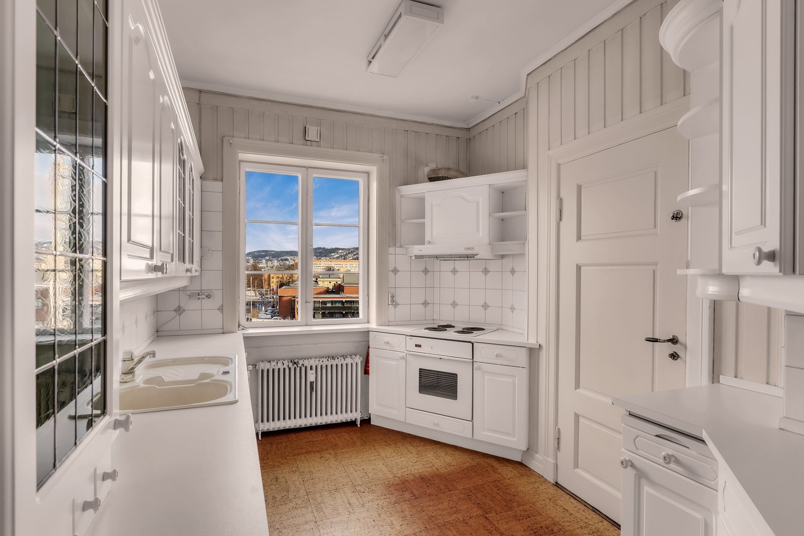 Hyggelig kjøkken med profilerte skapfronter og benkeplater av laminat med nedfelt oppvaskkum i stål. Utgang til bakgård via baktrapp fra kjøkkenet. Galleribilde