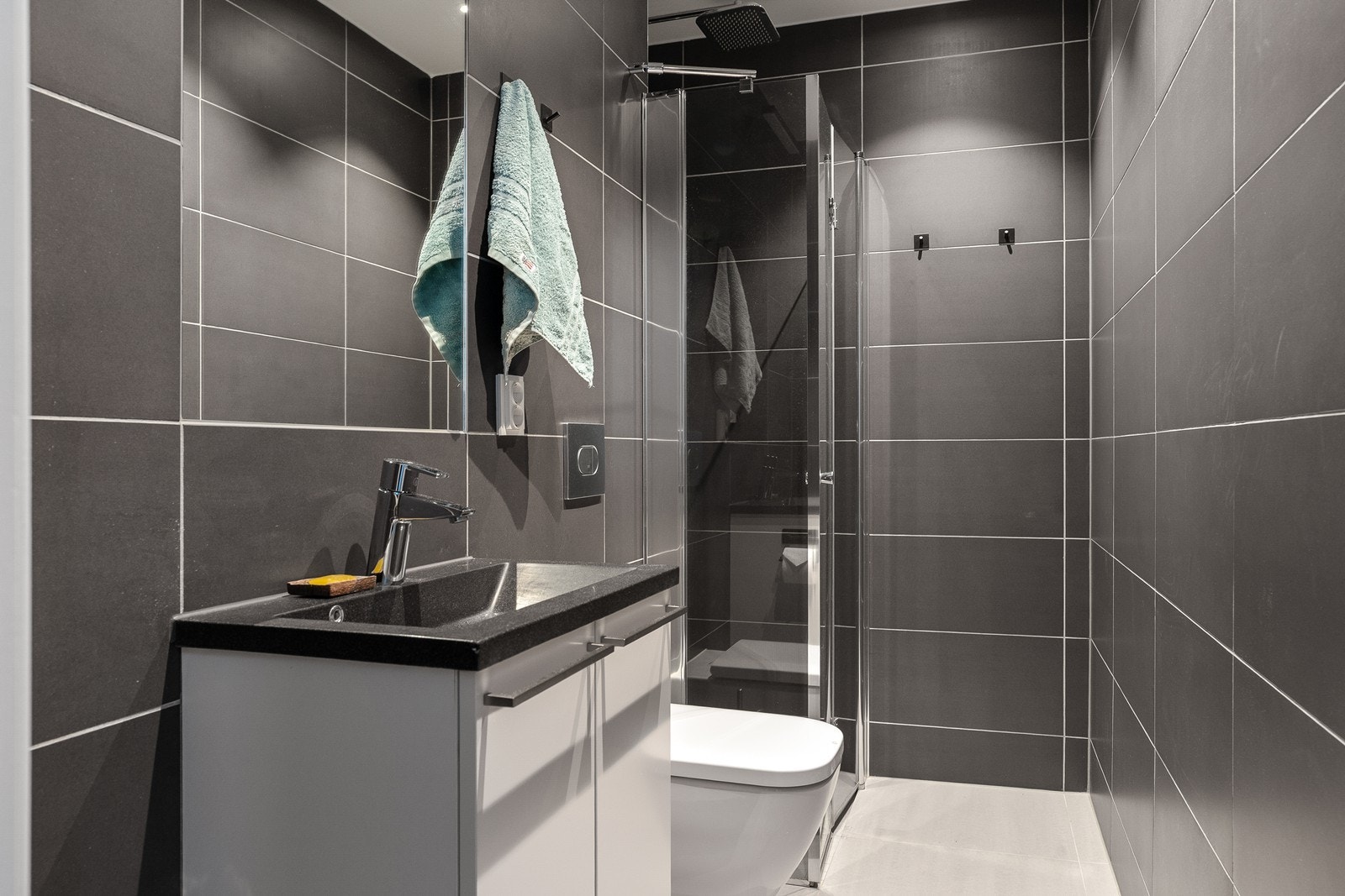 Badet er utstyrt med innfellbare dusjdører, mekanisk avtrekk, servantskap og veggmontert wc Galleribilde