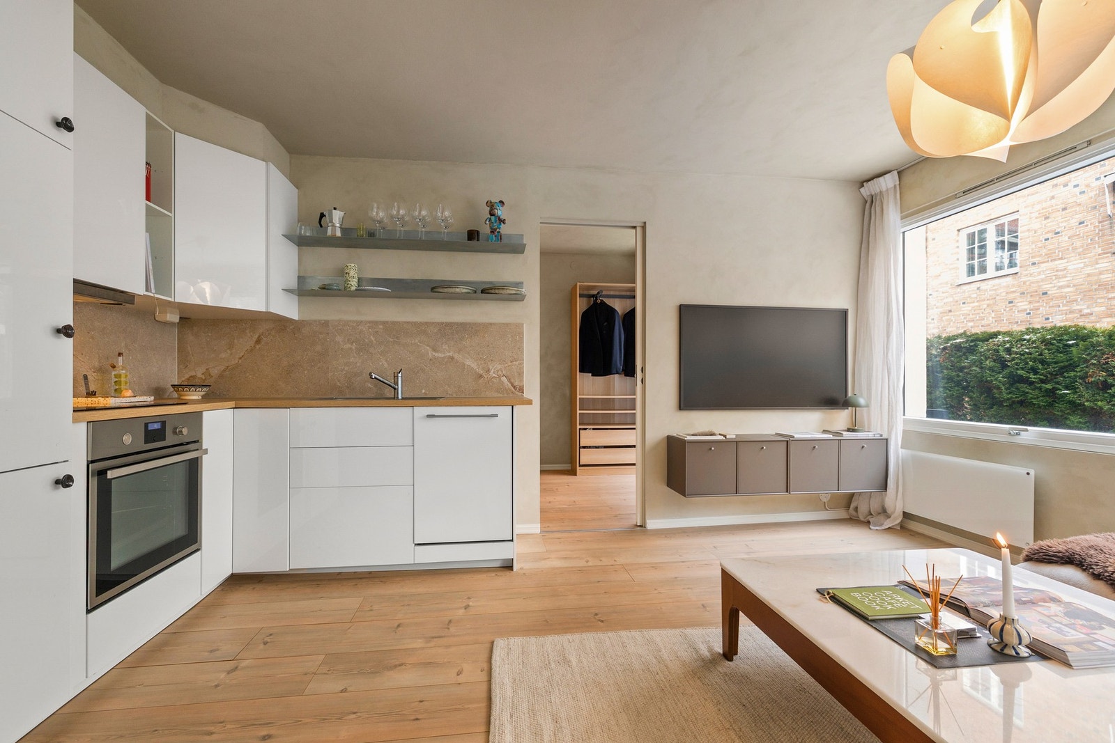 Store vindusflater sørger for fint naturlig lys og gir et grønt utsyn mot den etablerte hekken, noe som skaper en skjermet og behagelig atmosfære. Galleribilde