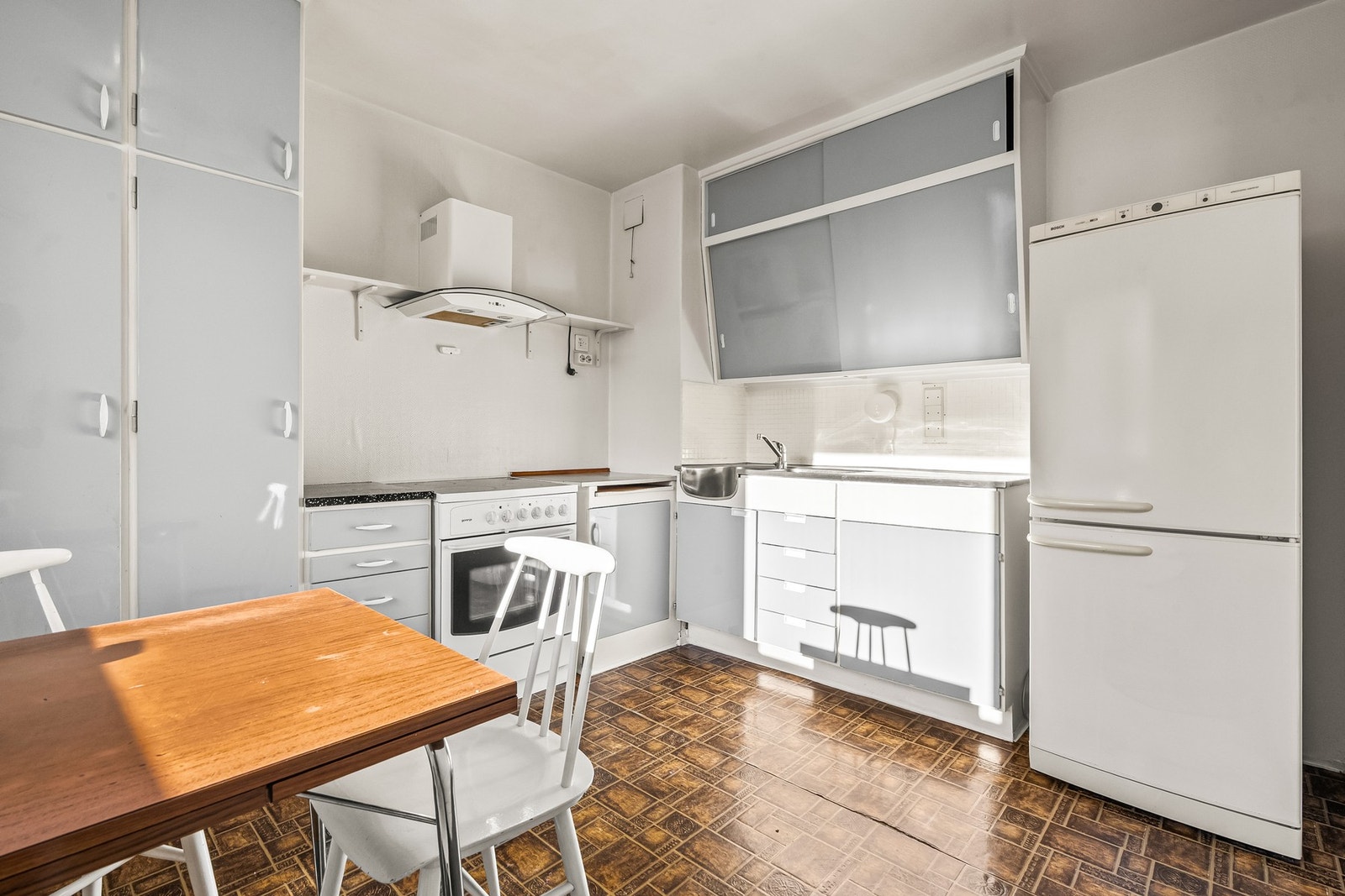 Kjøkkenet har plassbygde skap, karakteristiske skrå overskap med skyvedører, en vaskebenk med heldekkende benkebeslag og benkeplate i laminat. Over kokesonen er det montert en nyere kullfilterventilator. Det er avsatt plass til kjøle-/fryseskap. Galleribilde