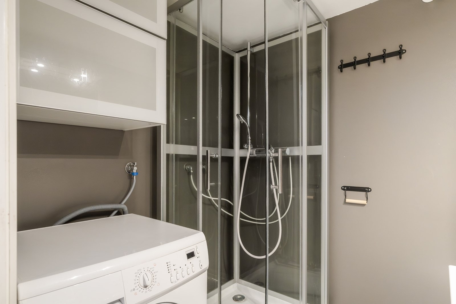 Badet er funksjonelt innredet med dusjkabinett, WC, servant med underskap og opplegg for vaskemaskin. Galleribilde