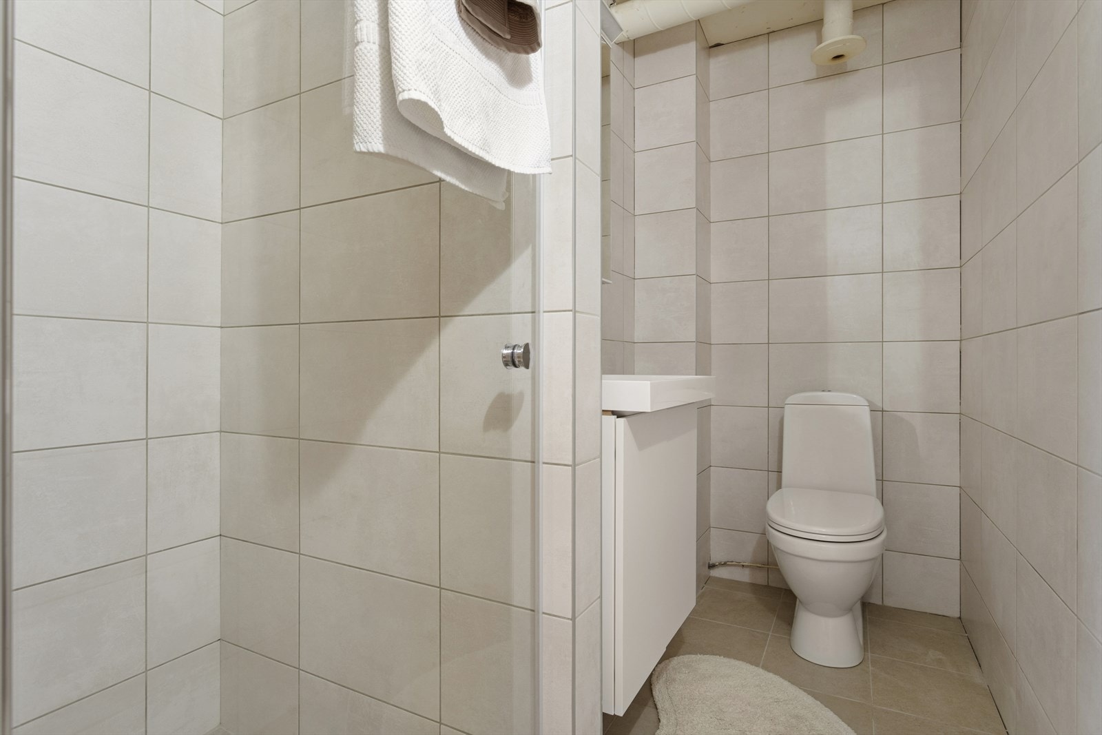 Baderom med dusjnisje, servant med underskap og toalett. Galleribilde