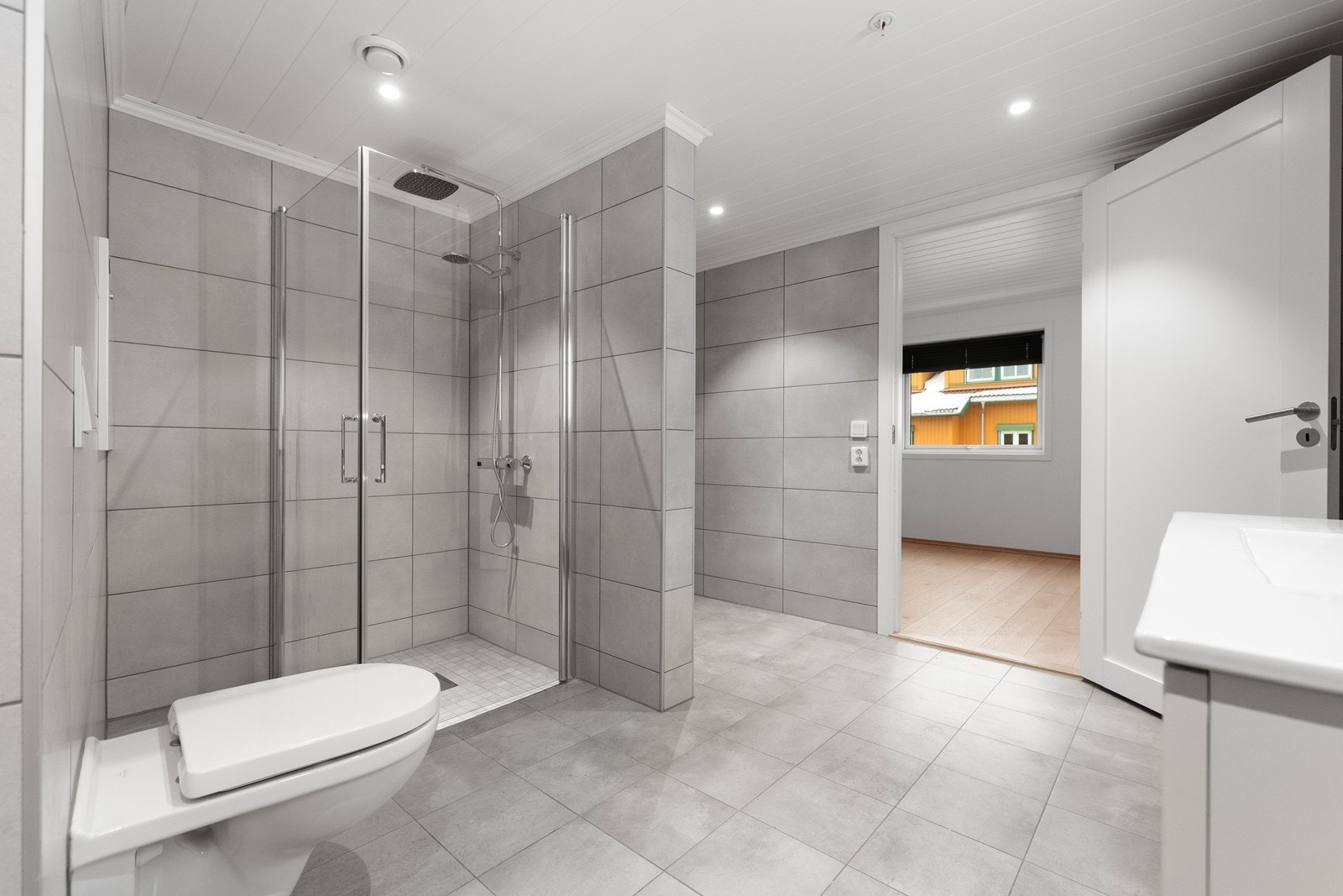 Pent flislagt baderom med gulvvarme. Badet er utstyrt med servant i baderomsinnredning, toalett og dusjhjørne med regnfallsdusj. Galleribilde