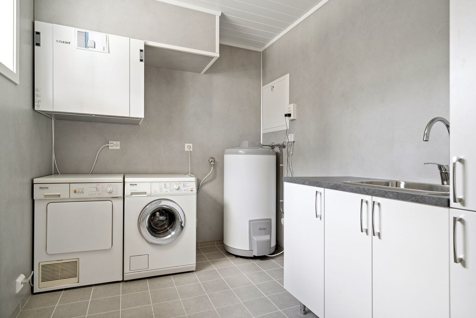 Romslig og praktisk vaskerom med innredning for oppbevaring. Galleribilde