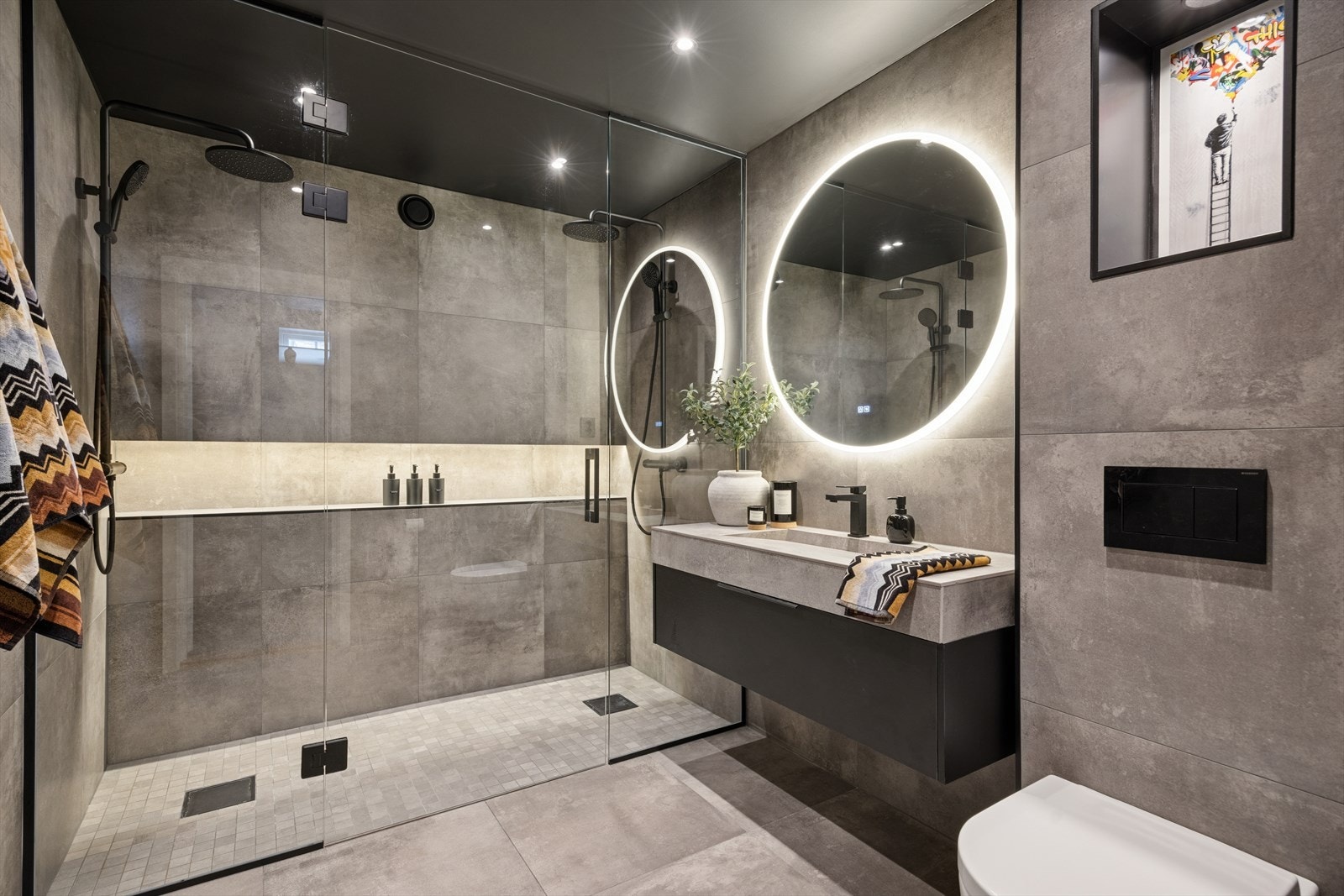 Delikat baderom i kjeller innredet med dobbel dusj, servant, toalett og dusjhjørne med dusjvegger. Galleribilde