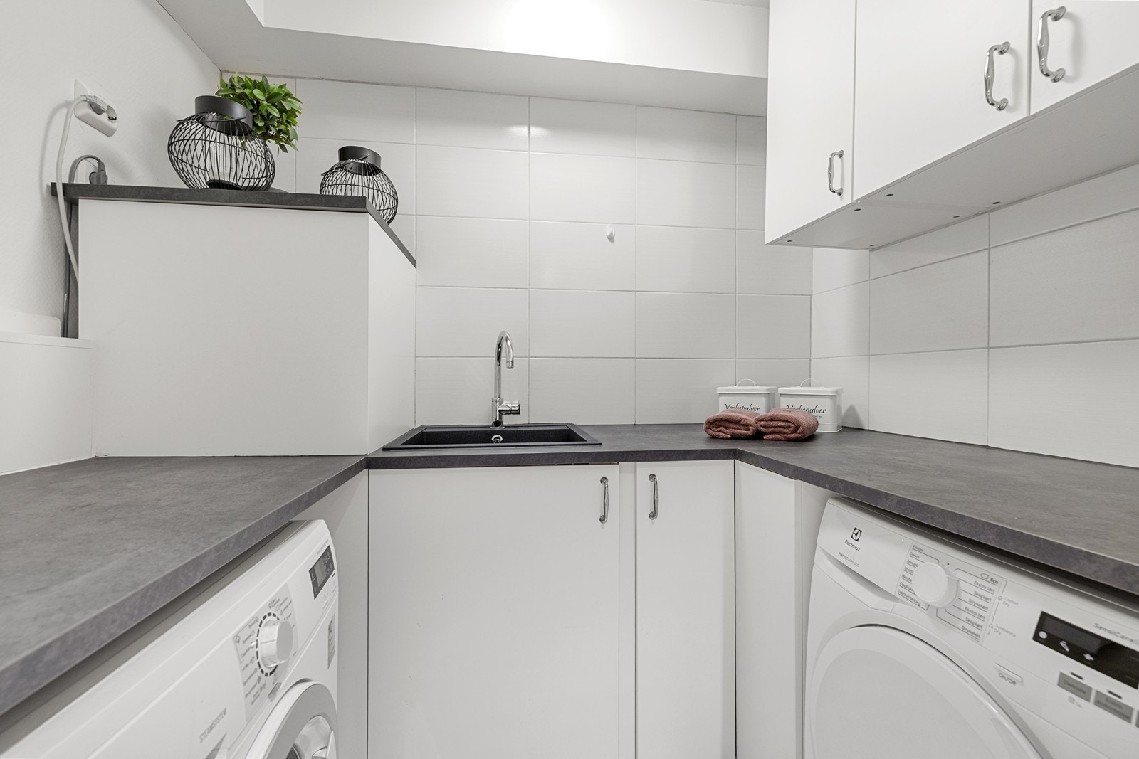 Praktisk og separat vaskerom med benkeskap og oppbevaringsplass. Opplegg for vaskemaskin og plass til tørketrommel. Galleribilde