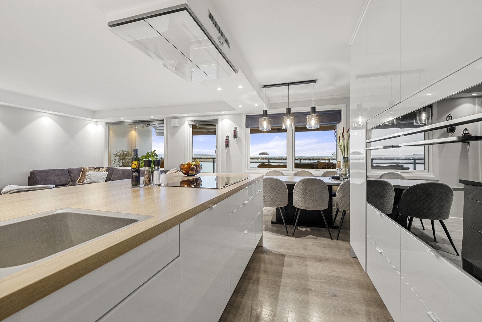 Innredningen har hvite, høyglansede fronter, laminat benkeplate og integrerte hvitevarer - inkludert koketopp, 2 stk stekeovner, oppvaskmaskin og vinskap. Galleribilde