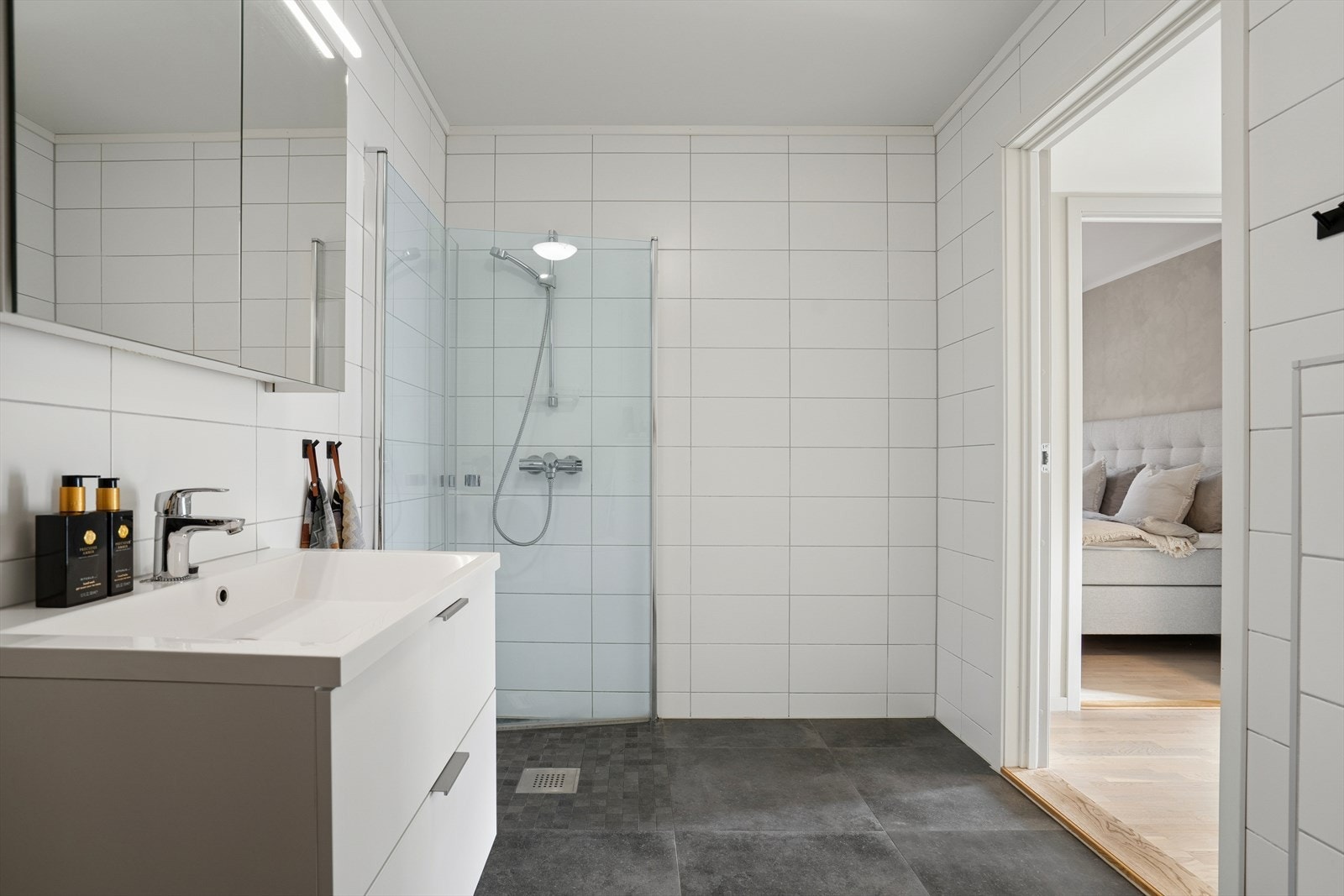 Her finner du dusjhjørne med innfellbare glassdører, vegghengt toalett, baderomsinnredning og opplegg for vaskemaskin Galleribilde