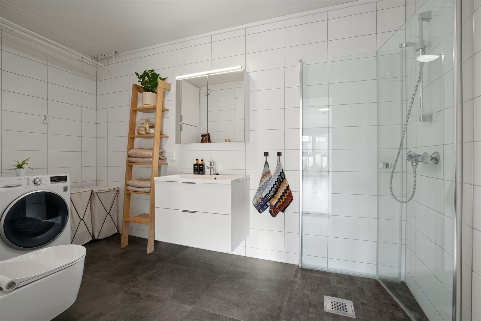 Badet er stilrent med mørke gulvfliser med varmekabler under og hvite veggfliser Galleribilde