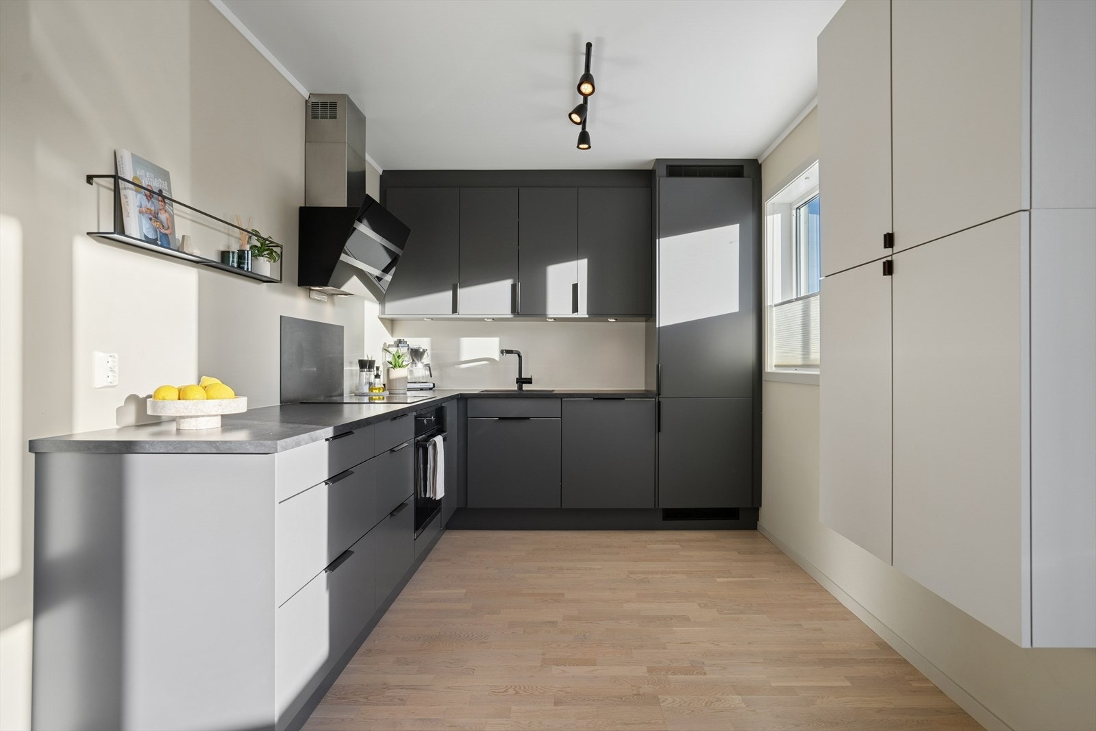 Kjøkkenet har innredning med glatte fronter og laminert benkeplate med nedfelt kjøkkenvask - Over kokesonen er det plate på vegg som gjør rengjøringen enklere Galleribilde