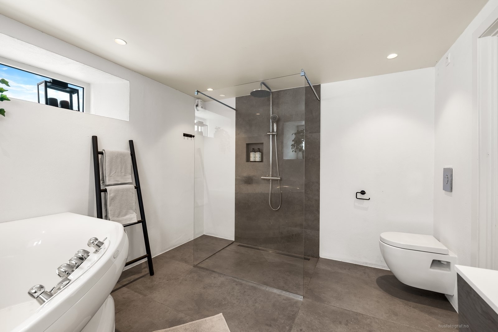 Rommet er utstyrt med baderomsinnredning med integrert servant i heldekkende plate, veggmontert toalett, badekar og dusjvegger/hjørne. Galleribilde
