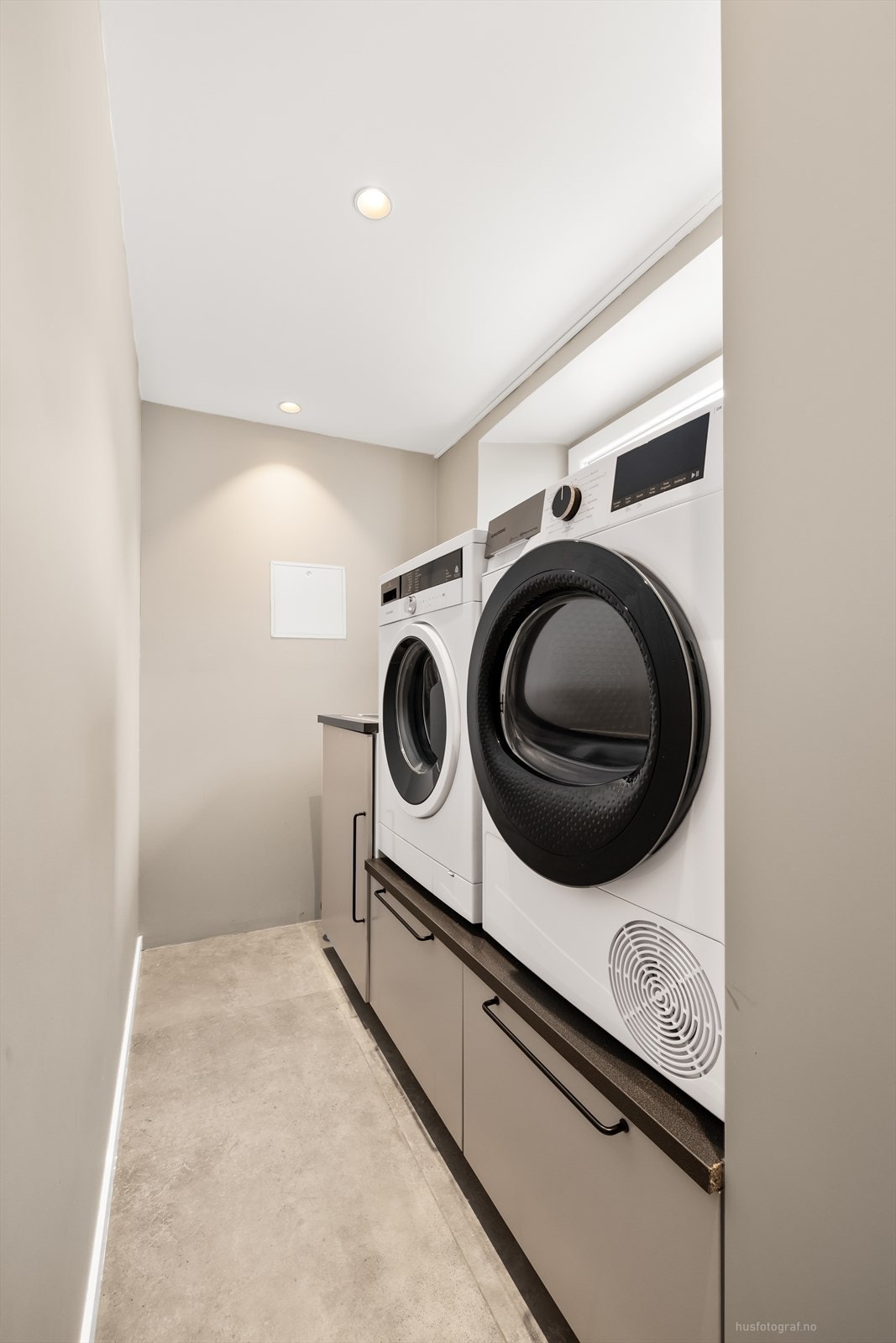 Moderne og funksjonelt vaskerom med beige innredning og plass til to vaskemaskiner. Galleribilde