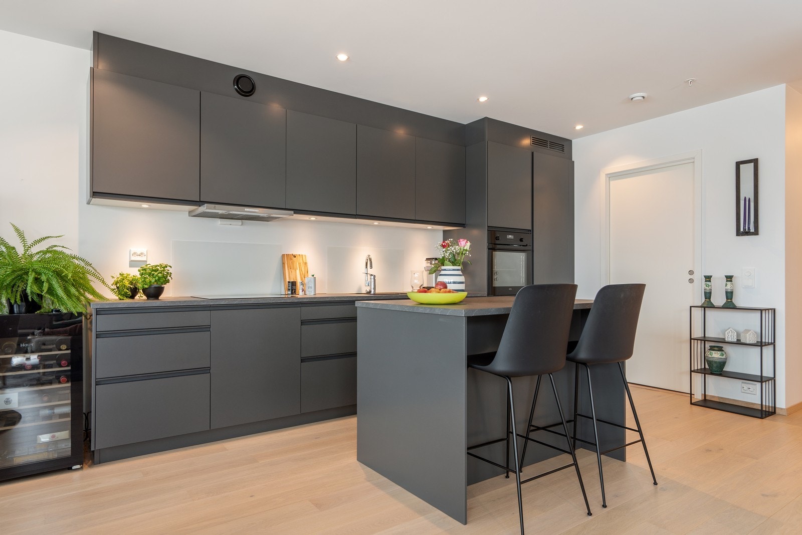 Flott takhøy kjøkkeninnredning med moderne, slette fronter i mørk utførelse. Galleribilde