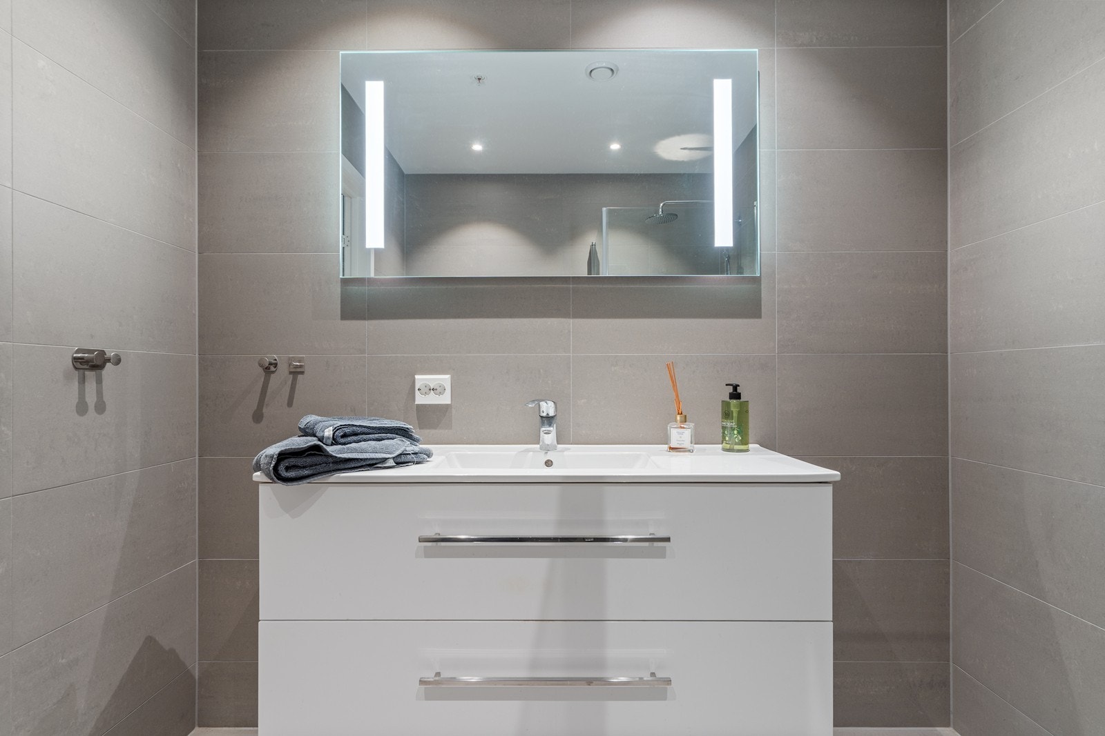 Det er innredet med servant med skuffer under, speil m/belysning, vegghengt toalett og dusjhjørne med innfellbare dusjdører i glass. Galleribilde