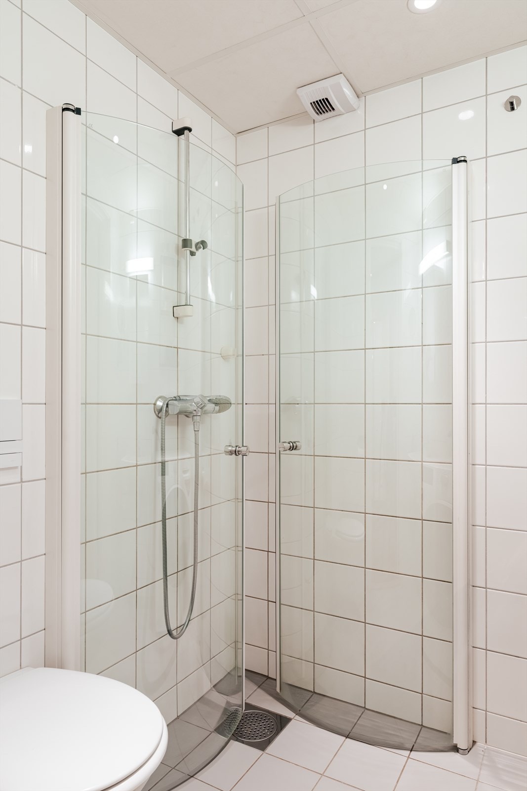 Innredningen består av servant, veggmontert wc, dusjhjørne med glassdører og opplegg for vaskemaskin Galleribilde