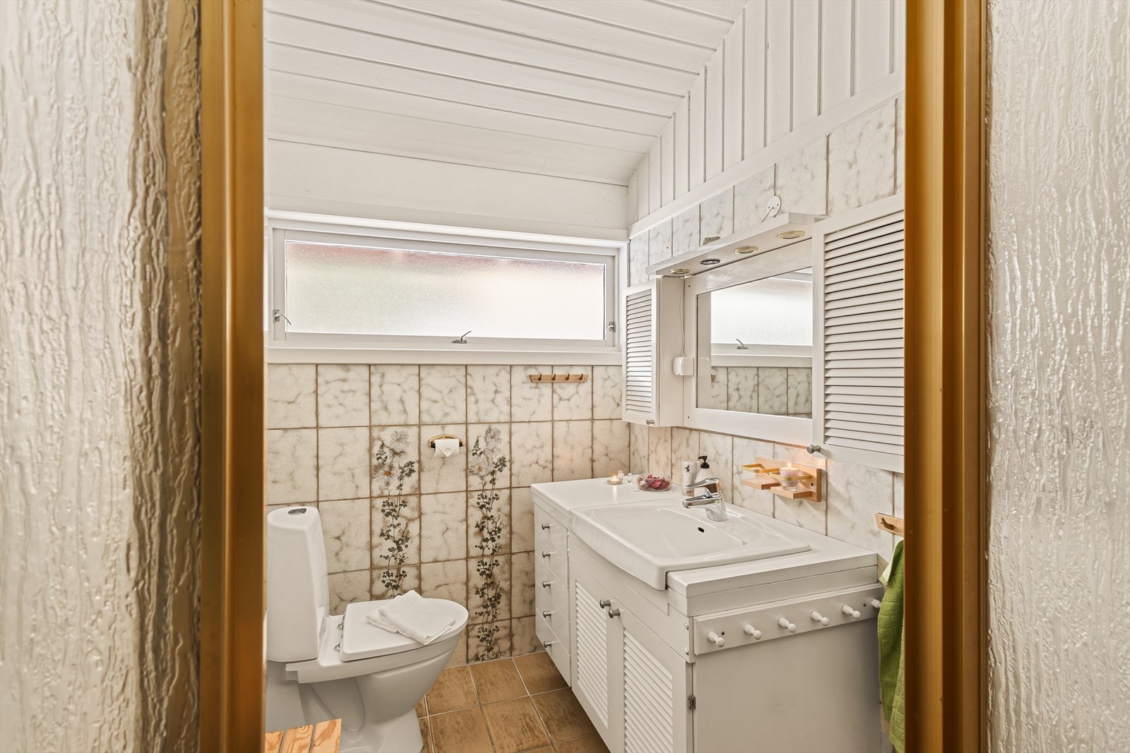 Badet er fra byggeår og er utstyrt med dusjhjørne, toalett og servantinnredning Galleribilde