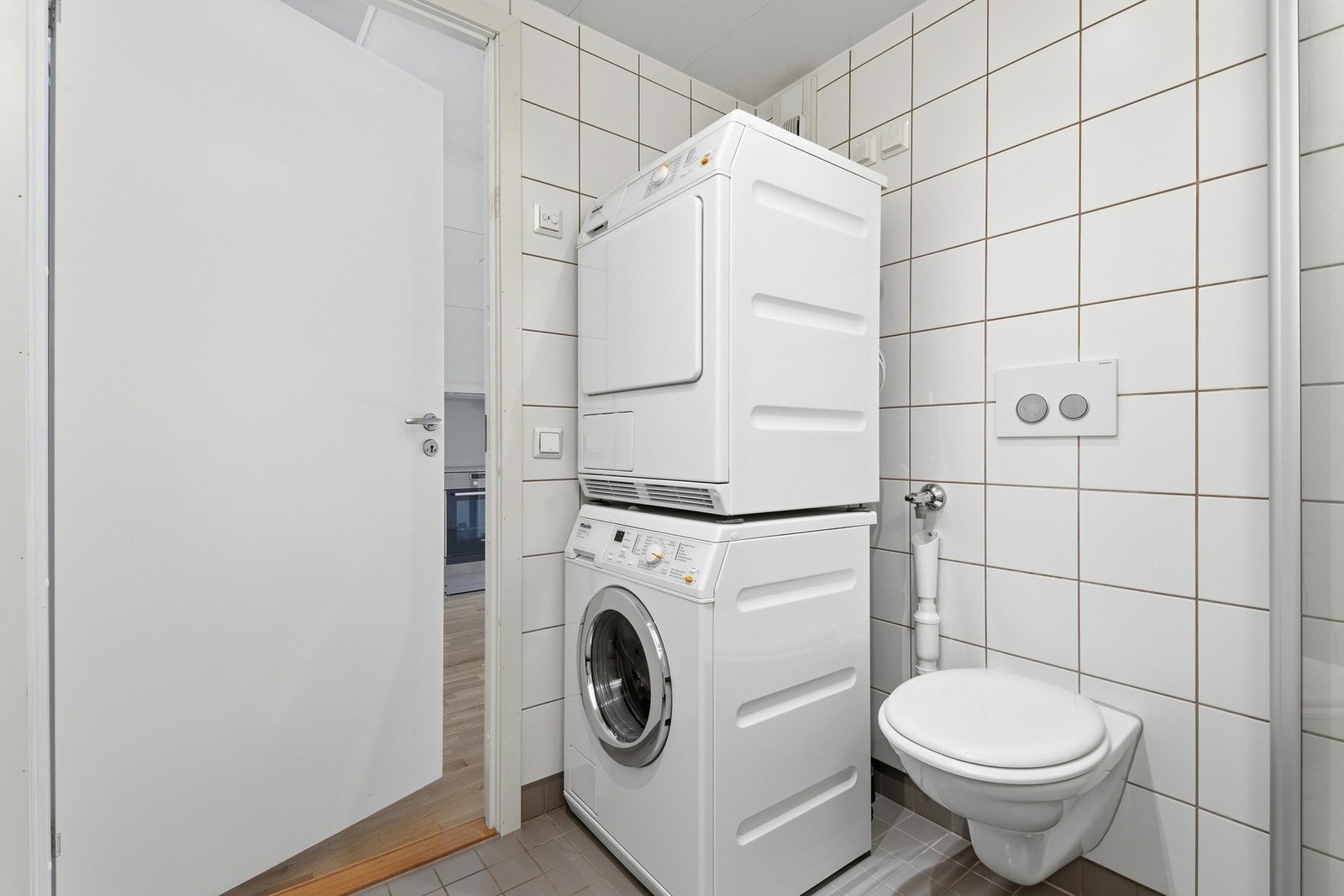 Badet er flislagt og og fremstår velholdt. Rommet inneholder dusjnisje, servantinnredning med speil og vegghengt toalett med innebygget sisterne. Galleribilde