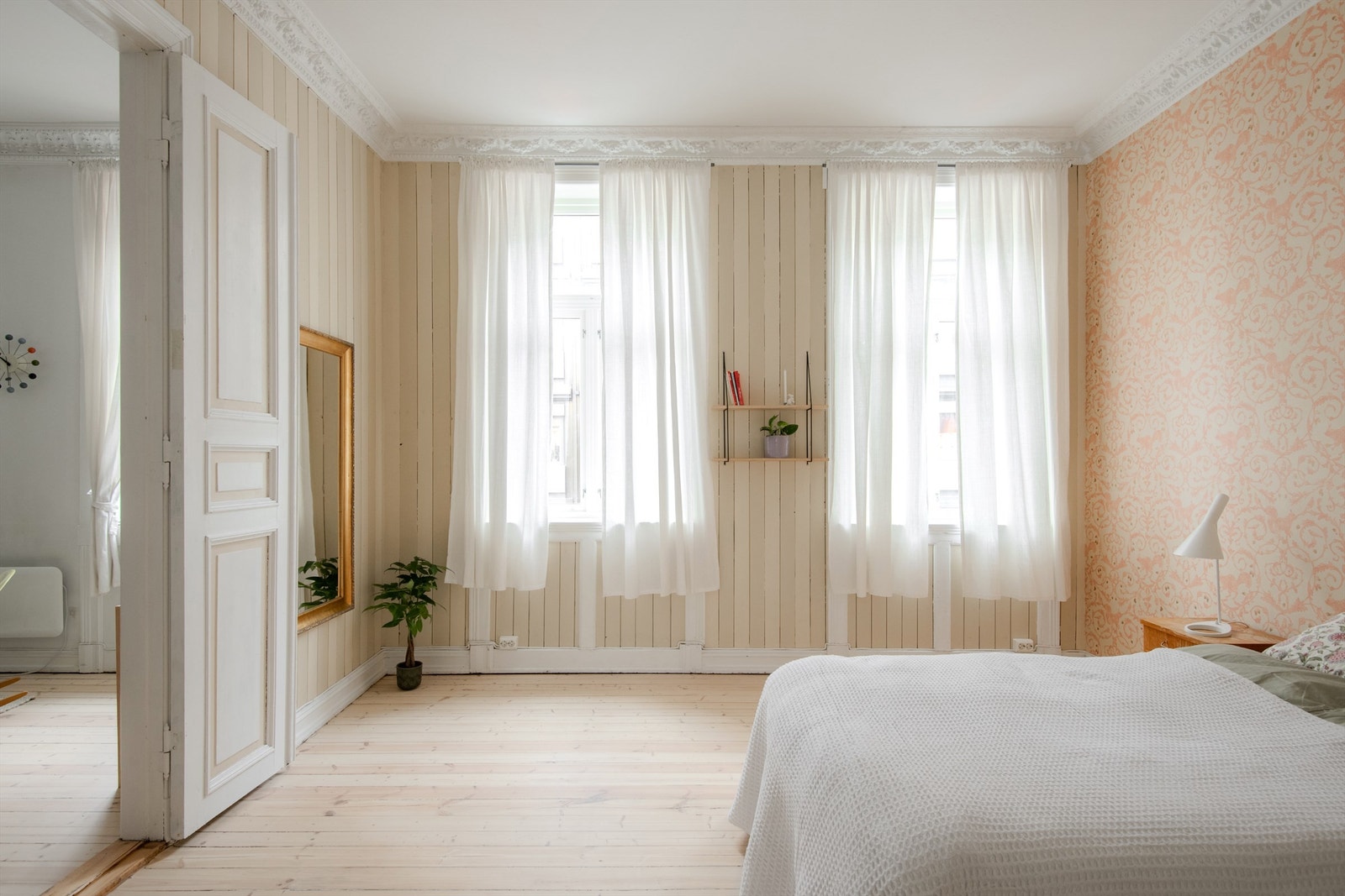 Rommet har lyse tregulv og delikate overflater, med en dekorativ tapetvegg som tilfører varme og karakter. Galleribilde