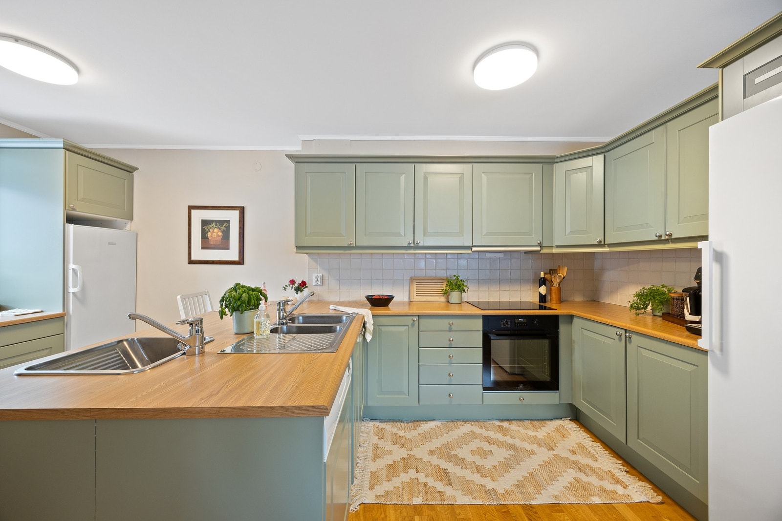 Pen, velholdt og klassisk kjøkkeninnredning med profilerte fronter, benkeplate av tre og nedfelt kjøkkenvask. Galleribilde