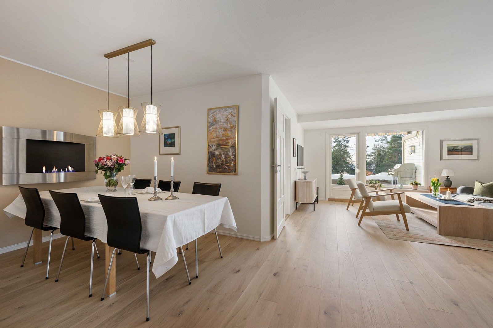 Spiseplass i åpen løsning mot stuen, med dekorativ vegghengt parafinpeis som skaper lun stemning. En hyggelig sone for både hverdagsmiddager og selskap. Galleribilde