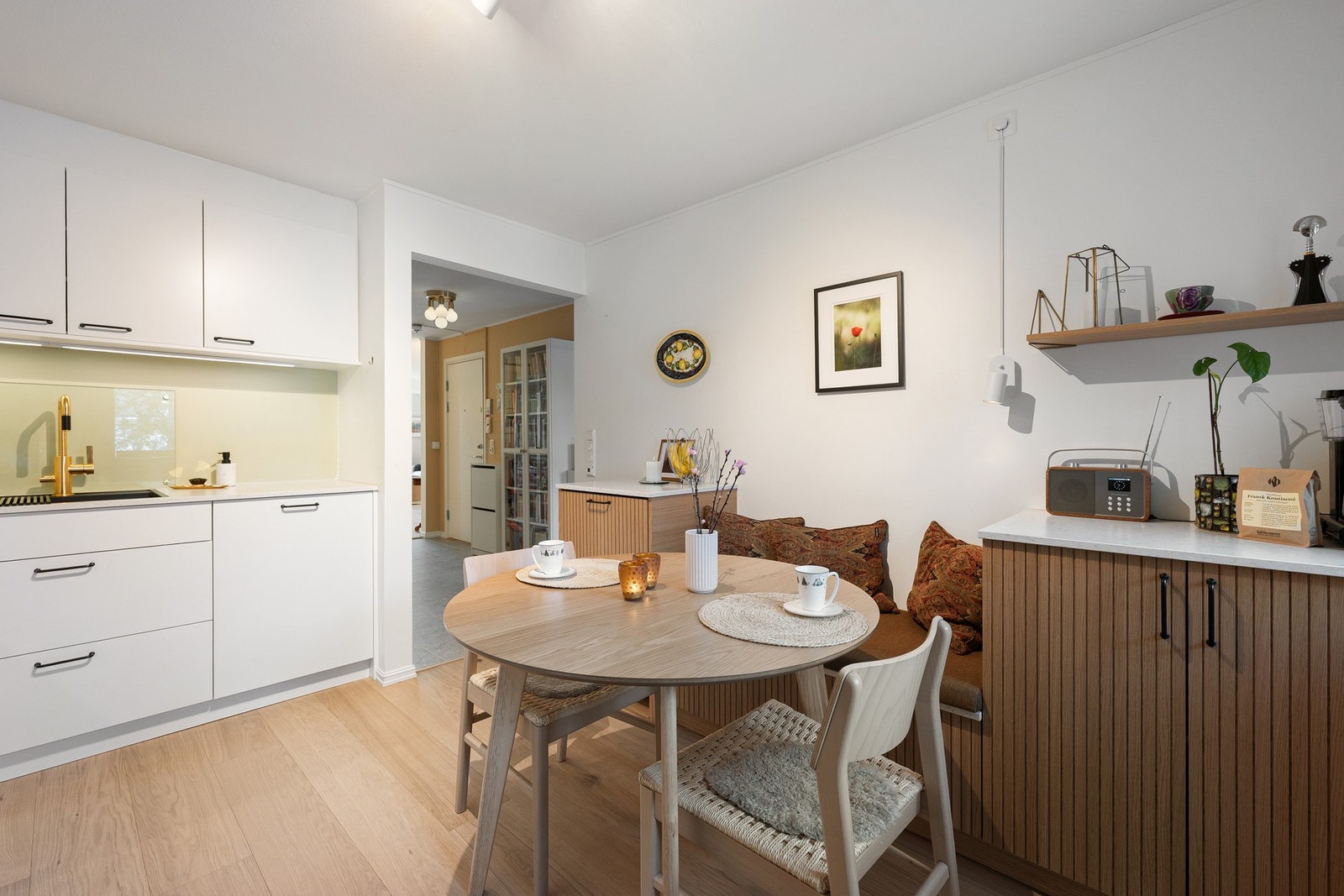Hyggelig spiseplass på kjøkkenet, perfekt for hverdagsmåltider. Kombinasjonen av lys innredning og detaljer i tre skaper et lunt og innbydende miljø. Galleribilde