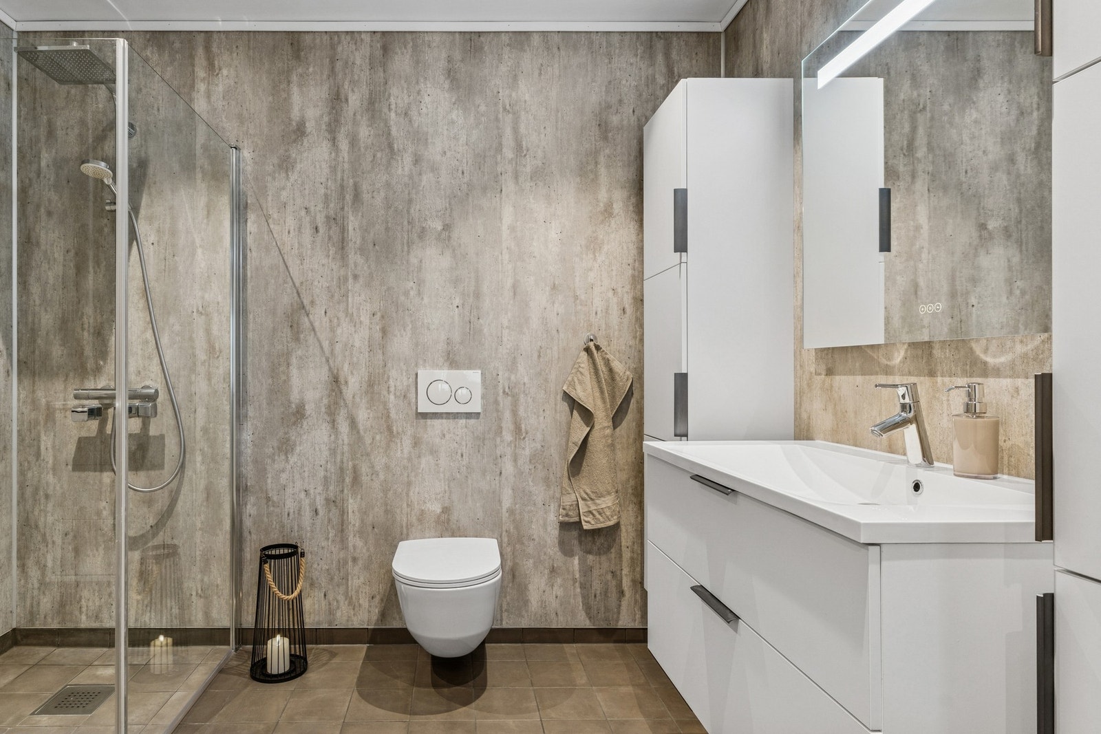 Badet har vegghengt toalett, baderomsinnredning og dusjhjørne. Galleribilde