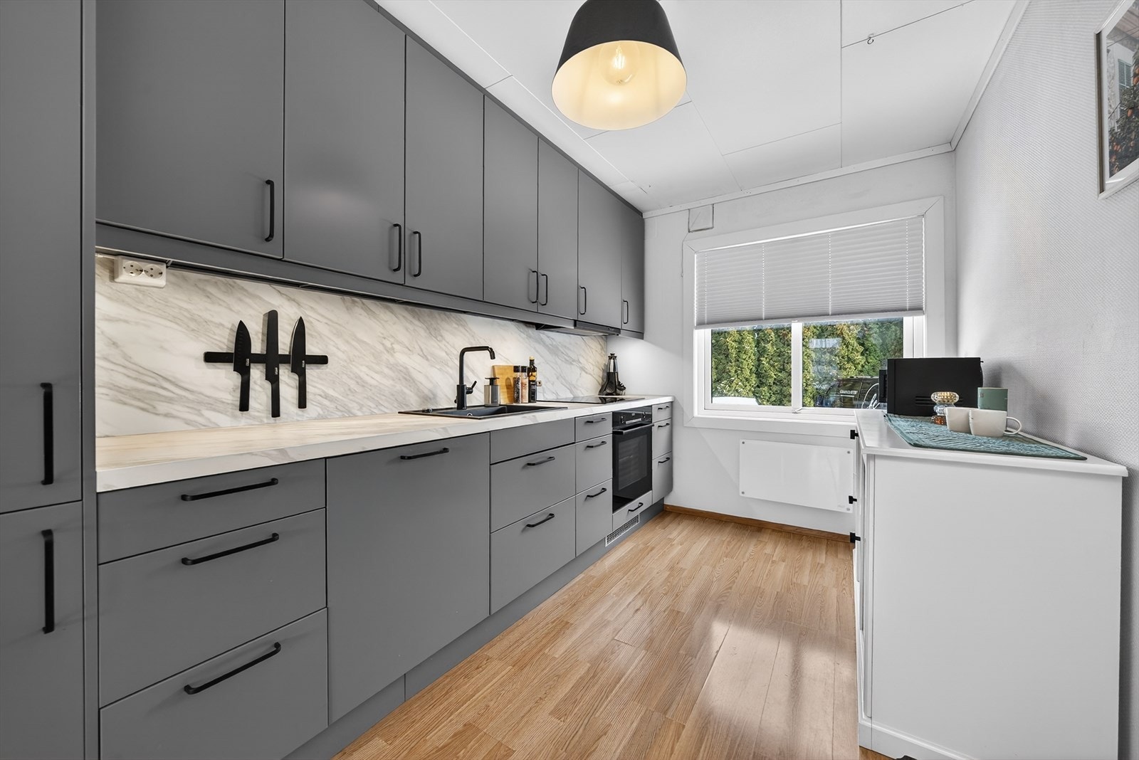 Pene og praktiske Kitchen Boards med marmor stil på vegg og langs kjøkkenbenken. Innredningen har integrert kjøleskap, stekeovn, platetopp og oppvaskmaskin. Galleribilde