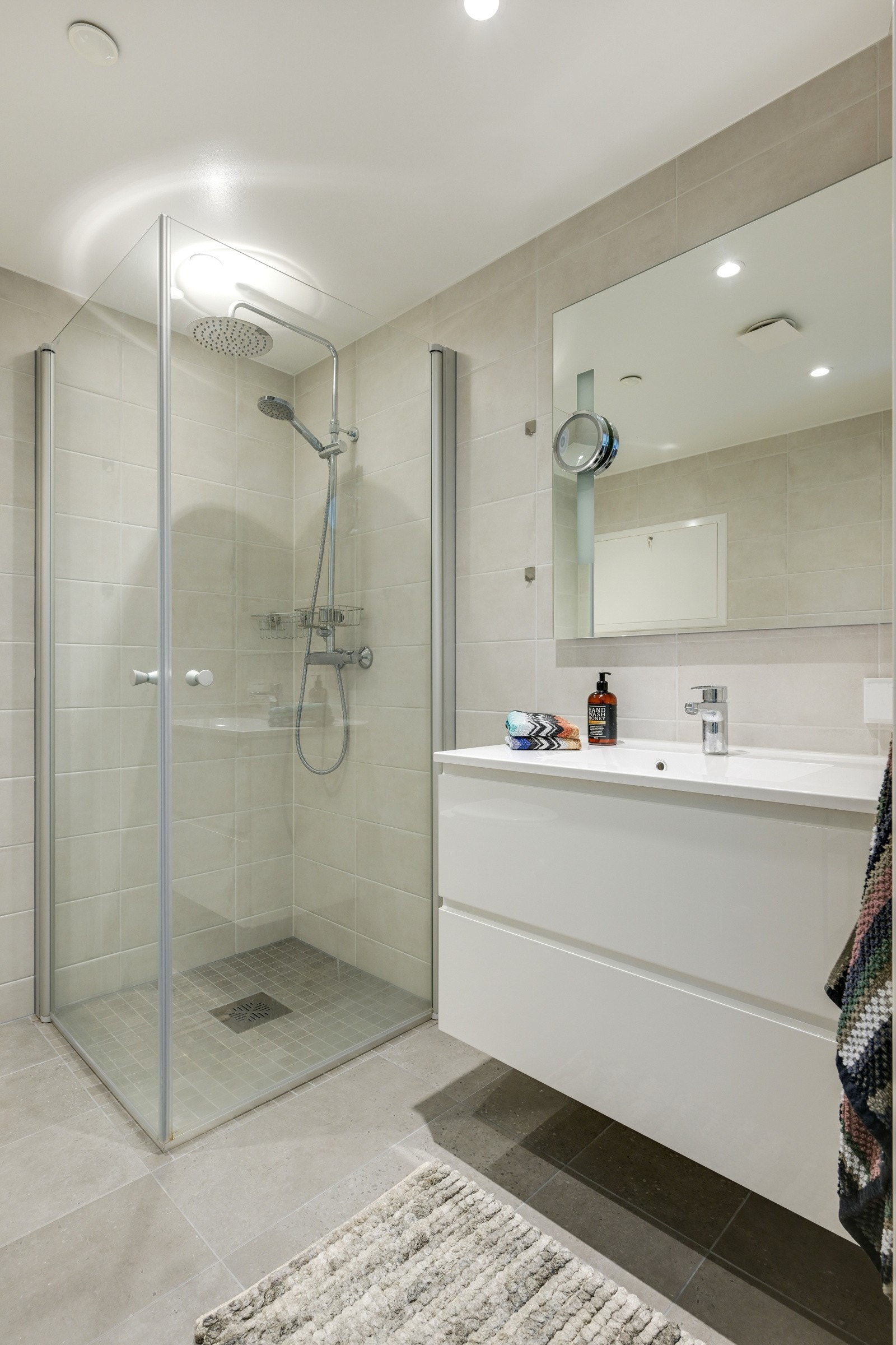 Første badet er romslig med pen baderomsinnredning, fliser på gulv og dusjhjørne Galleribilde