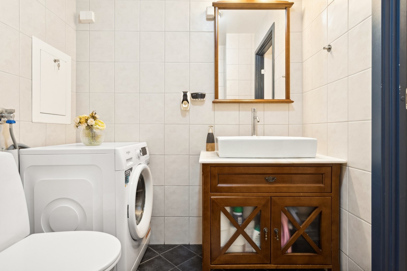 Baderommet har dusjvegger av glass, gulvmontert toalett, innredning med servant samt opplegg for vaskemaskin. Galleribilde