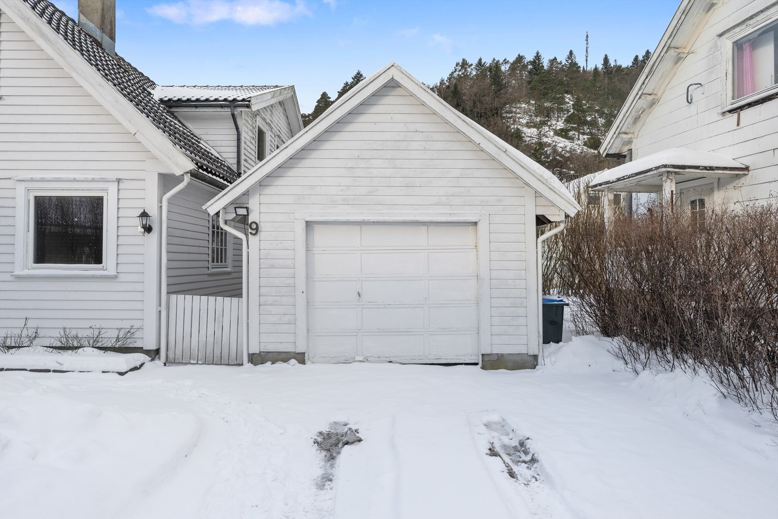 Garasjen har en port i tre, med elektrisk portåpner Galleribilde