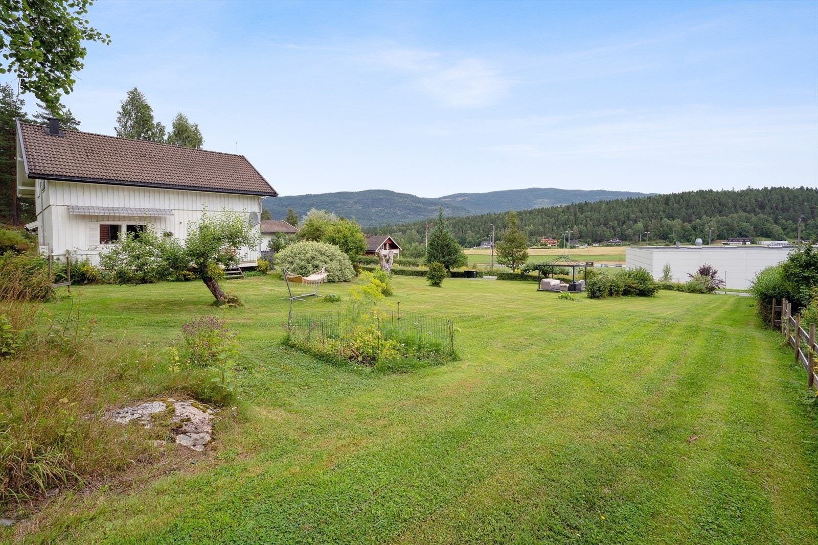 Tomten ligger i skrånende terreng og er delvis opparbeidet med gressplen og prydbusker. Galleribilde