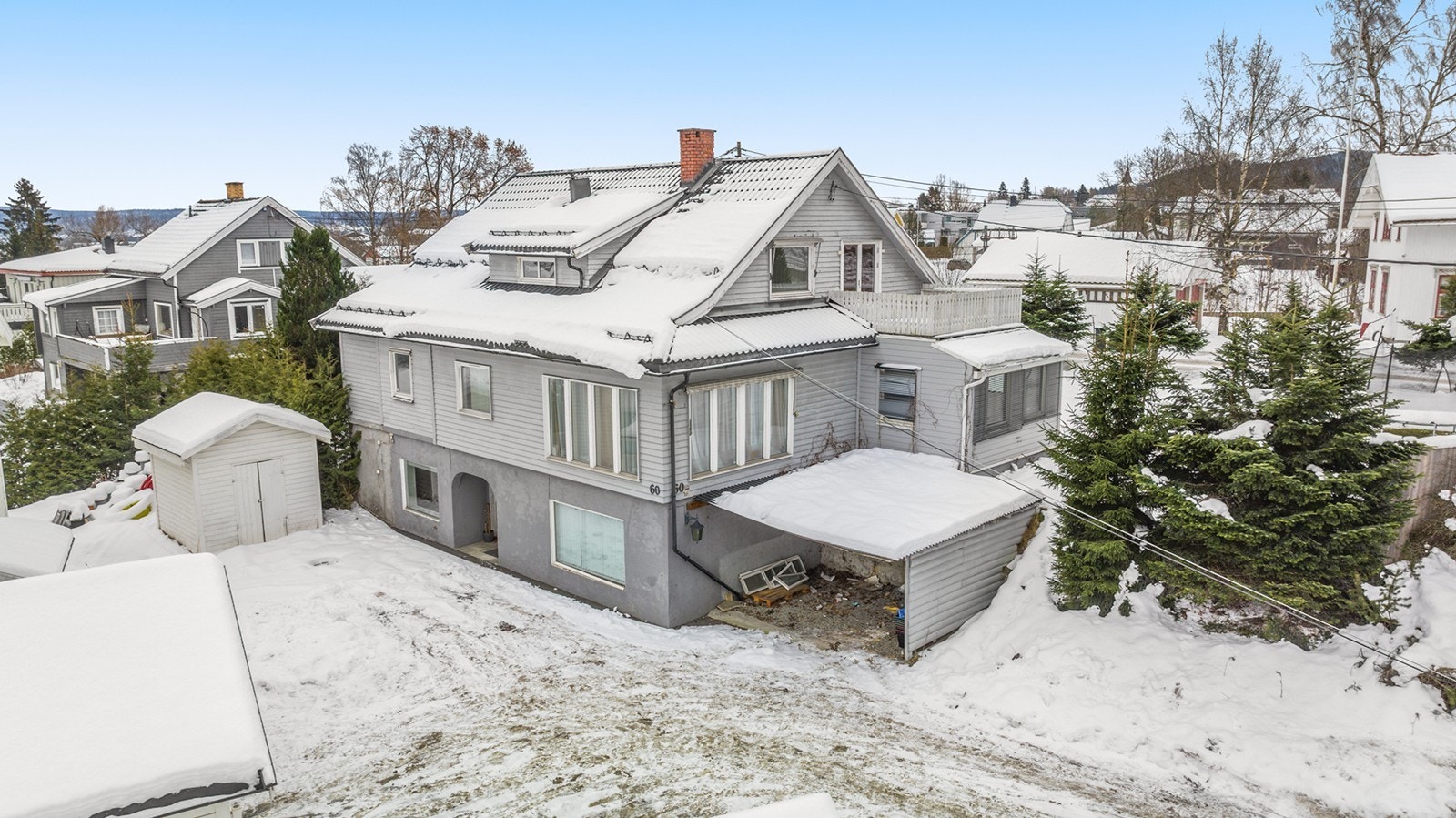 Eiendommen har en carport med pulttak, tekket med stål- eller aluminiumsplater. Terrenget rundt boligen er svakt skrånende, med naturlige høydeforskjeller. Galleribilde