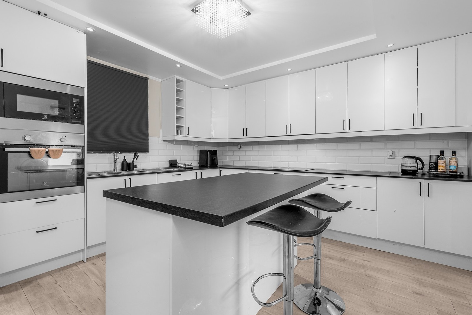 Kjøkkenet har glatte, hvite høyglansfronter og en laminat benkeplate med nedfelt dobbel kum i rustfritt stål. Galleribilde