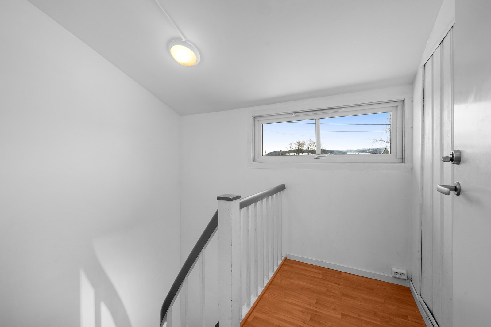Trappeoppgangen har slettmalte vegger og laminatgulv, med vindu som gir naturlig lys. Galleribilde