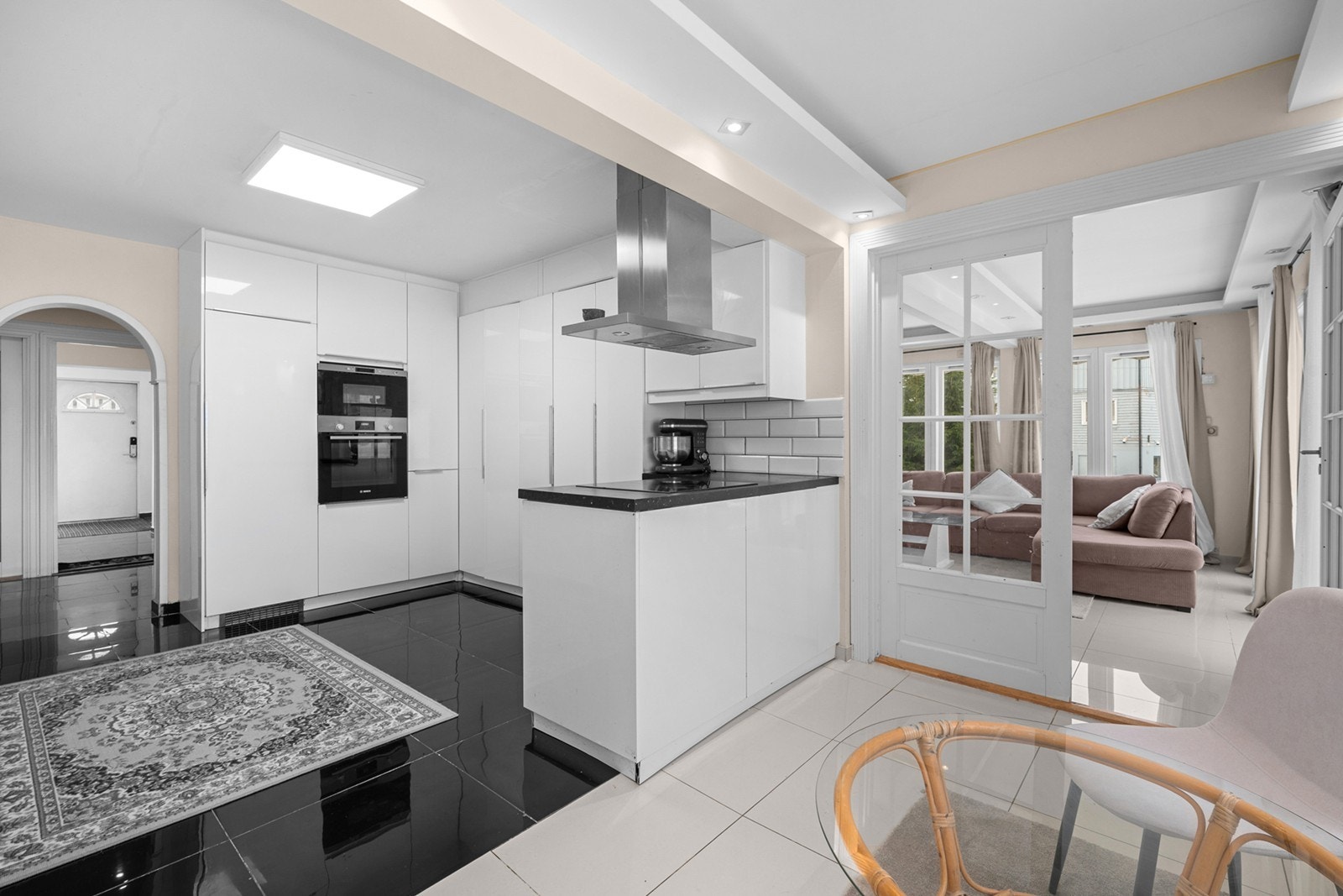 Kjøkkenet har glatte, hvite høyglansfronter og en benkeplate i laminat med dobbel kum i rustfritt stål. Galleribilde