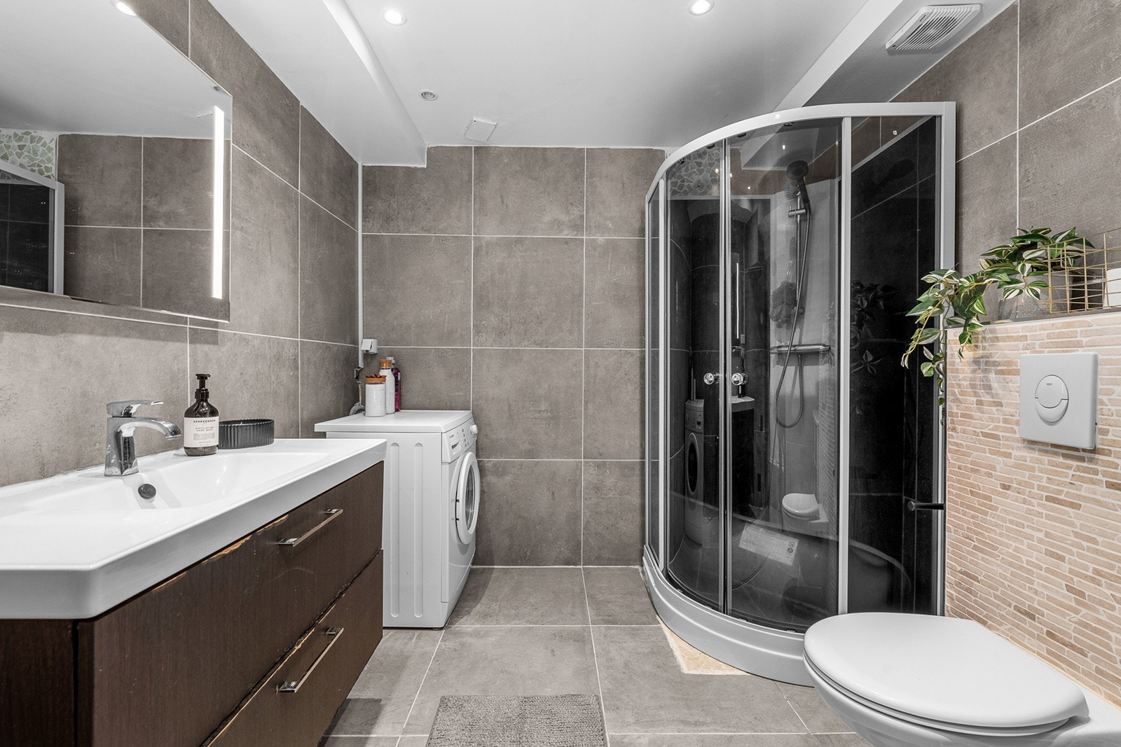 Frittstående dusjkabinett og vegghengt toalett med innebygget sisterne gir effektiv utnyttelse av rommet. Galleribilde