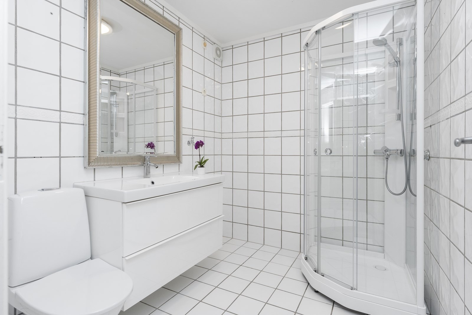 Badet har flislagte gulv med elektriske varmekabler, flislagte vegger og malte slette plater i taket Galleribilde