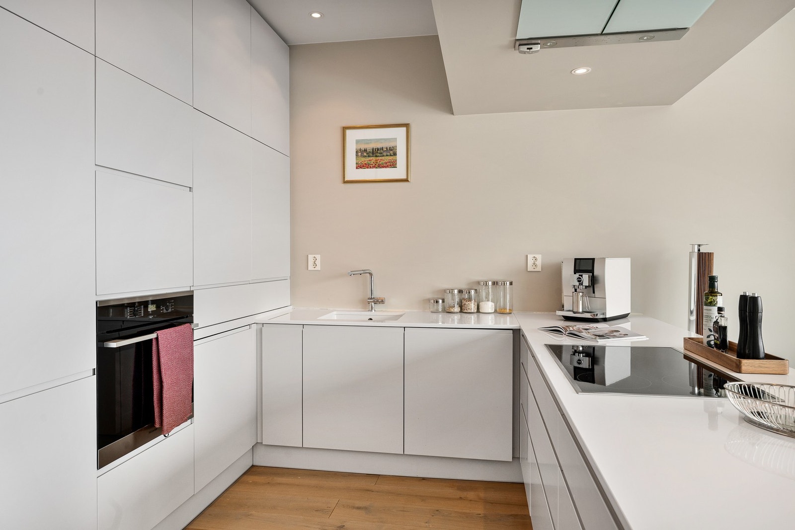 Kjøkkenet er moderne med lyse, hvite høyglans kjøkkeninnredning med integrerte håndtak. Galleribilde