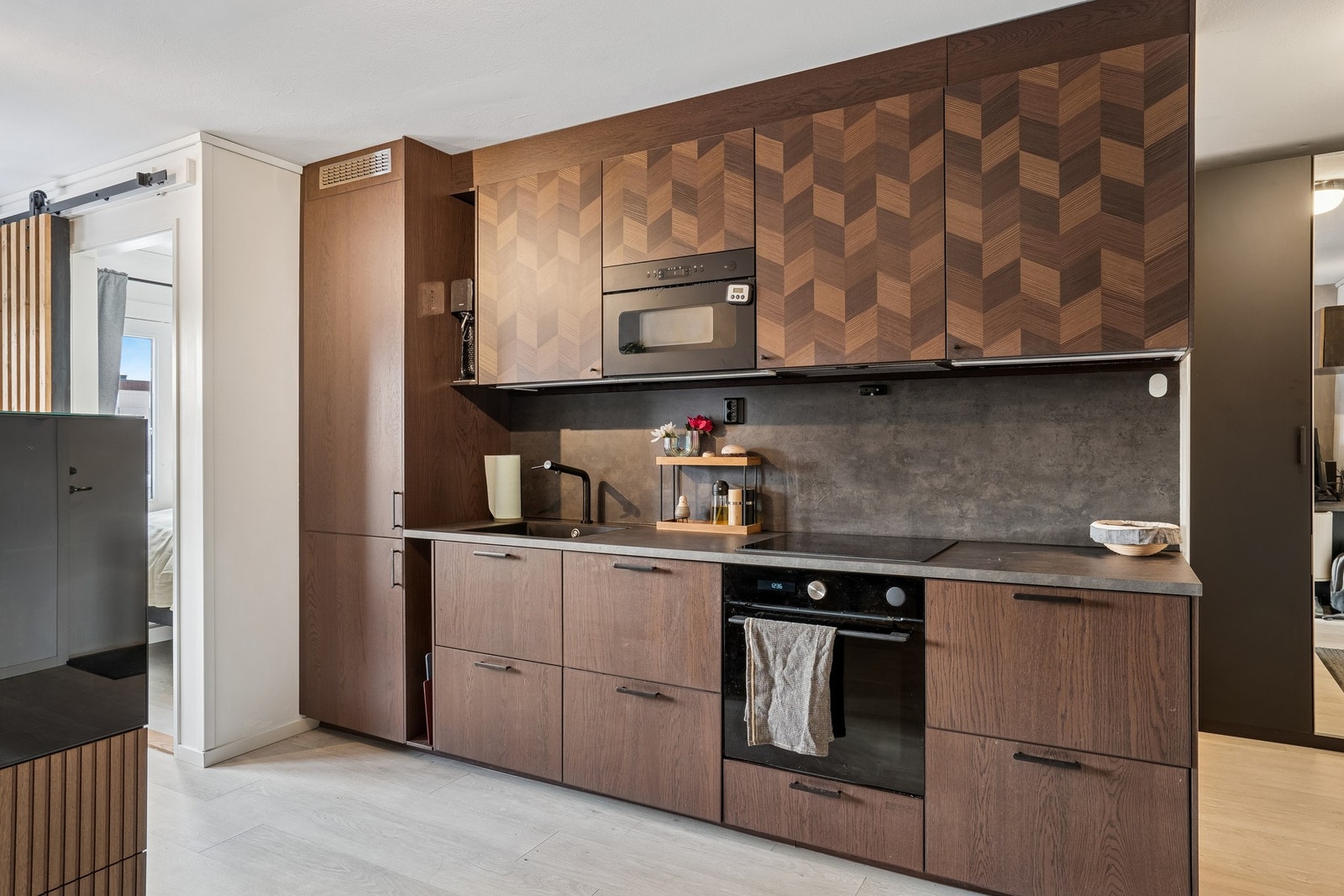 Praktisk kjøkken med mye skap- og benkeplass, tilpasset leilighetens moderne uttrykk. Galleribilde