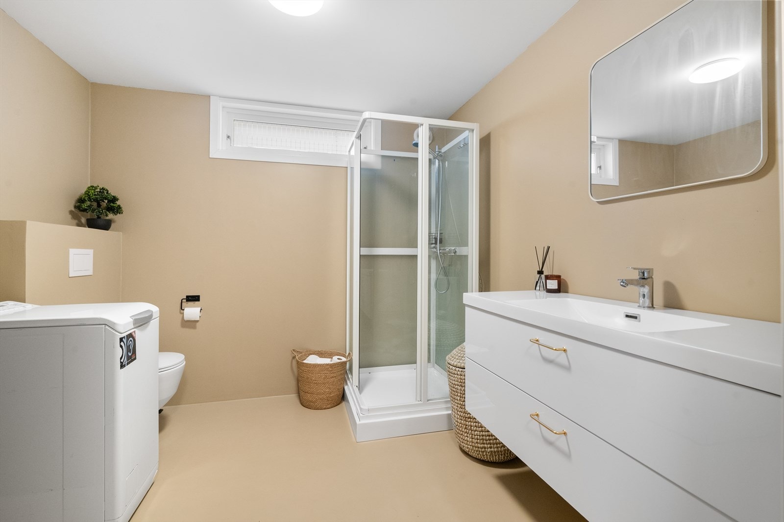 Badet er pusset opp i 2024 og inneholder heldekkende servant med underskap, speil, dusjkabinett, toalett og opplegg til vaskemaskin. Galleribilde